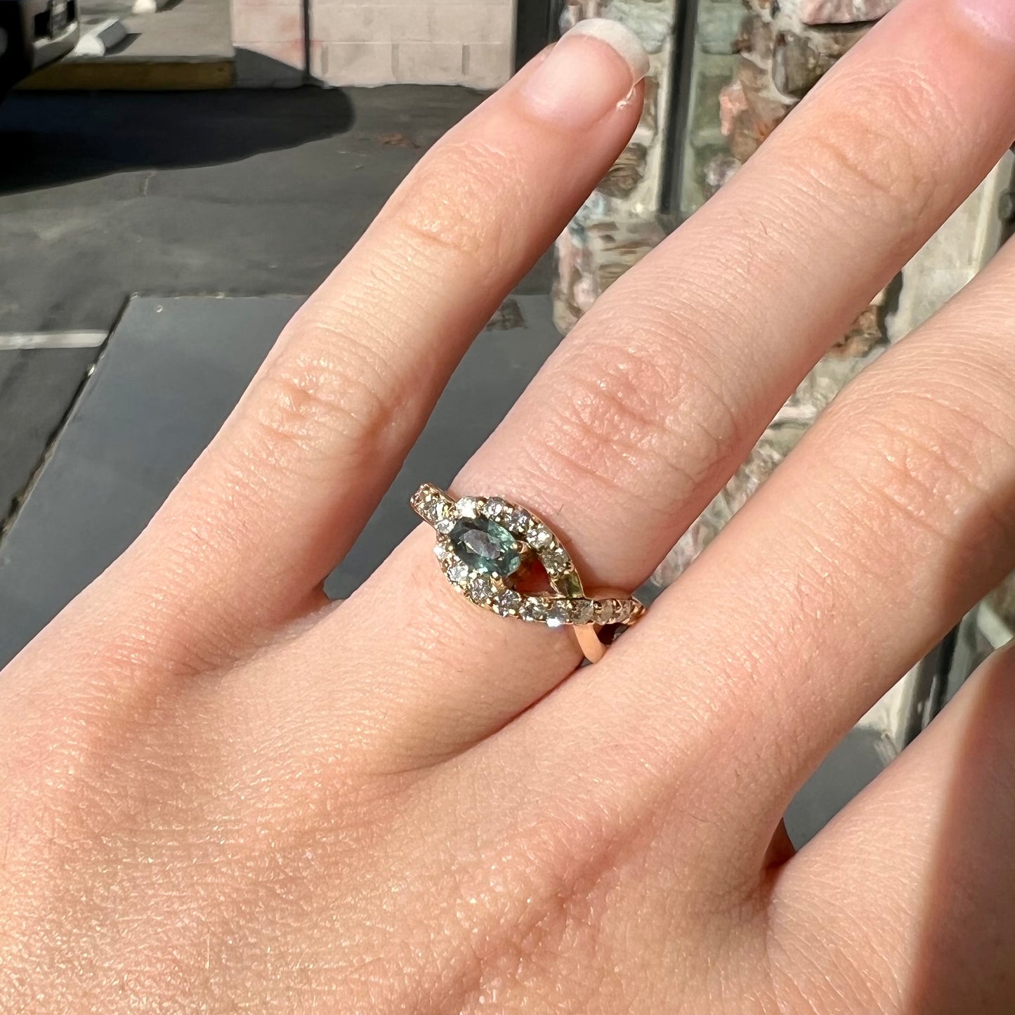 Yellow gold alexandrite and pave set diamond ladies' ring on a hand in natural sunlight.