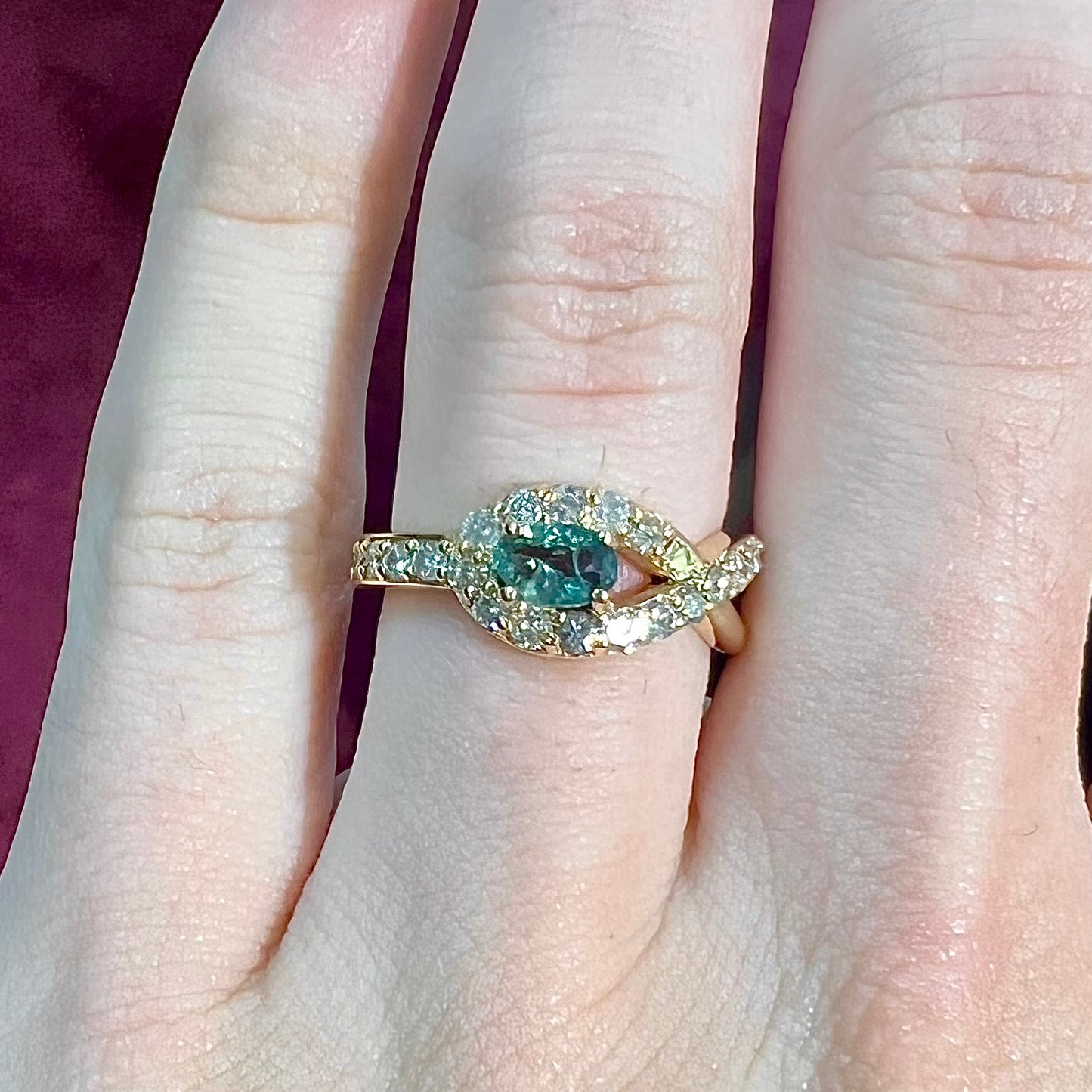 Yellow gold alexandrite and pave set diamond ladies' ring on a hand.