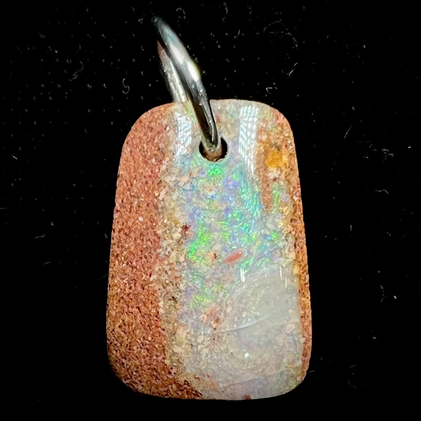 A drilled boulder opal stone with a sterling silver ring through the hole to be worn as a pendant.