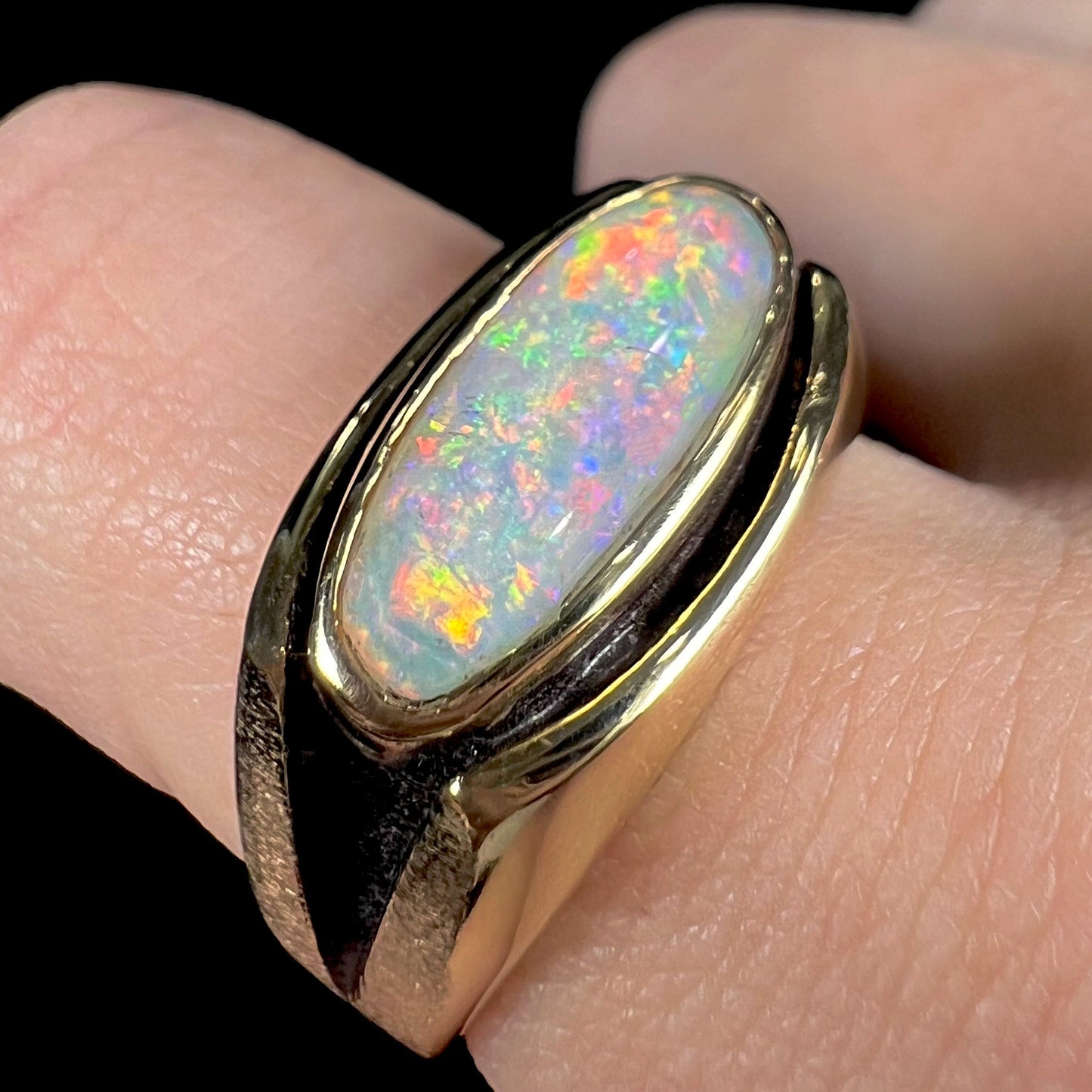 An Australian white crystal opal men's ring in solid yellow gold. The recesses of the ring have been blackened.