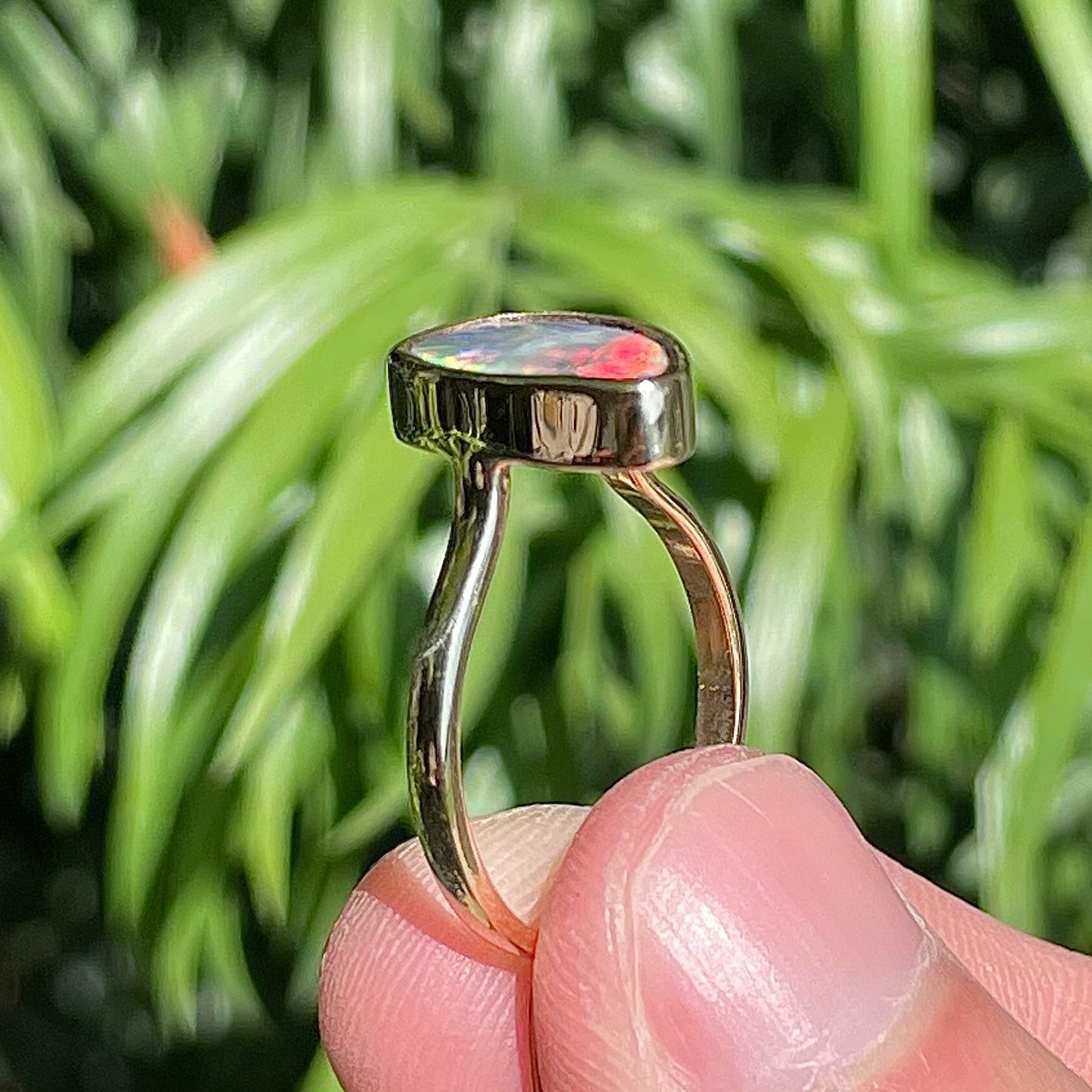 A freeform cut semi-black opal from Lightning Ridge, Australia set in a bezel set yellow gold solitaire ring.