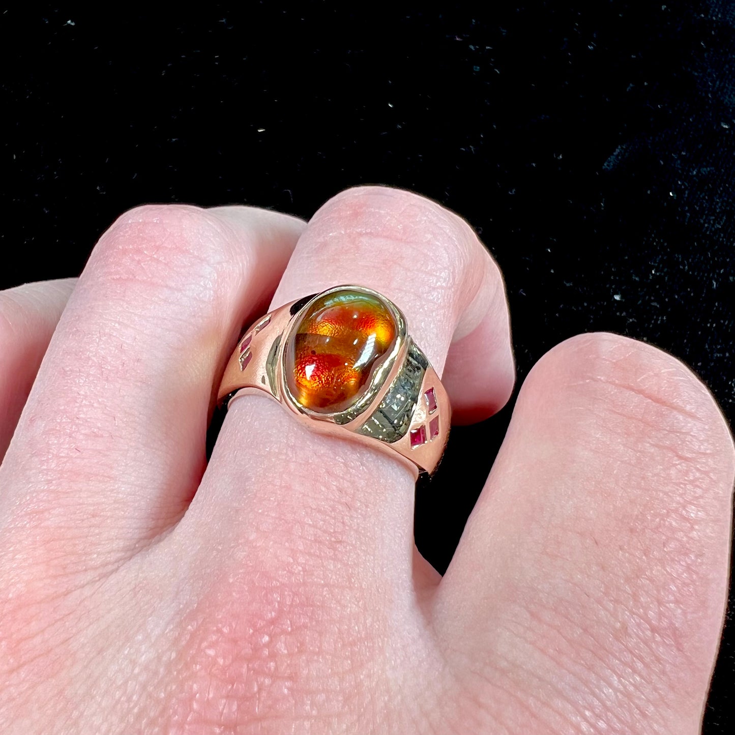 A yellow gold men's ring set with princess cut Burma rubies and a freeform cabochon cut red fire agate from Slaughter Mountain, Arizona.