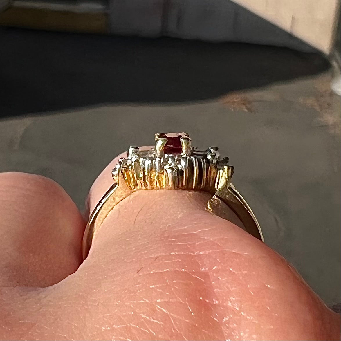 A yellow gold ring set with an oval cut red spinel and diamond rounds and baguettes.