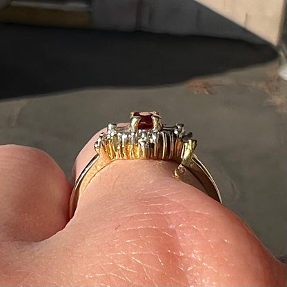 A yellow gold ring set with an oval cut red spinel and diamond rounds and baguettes.