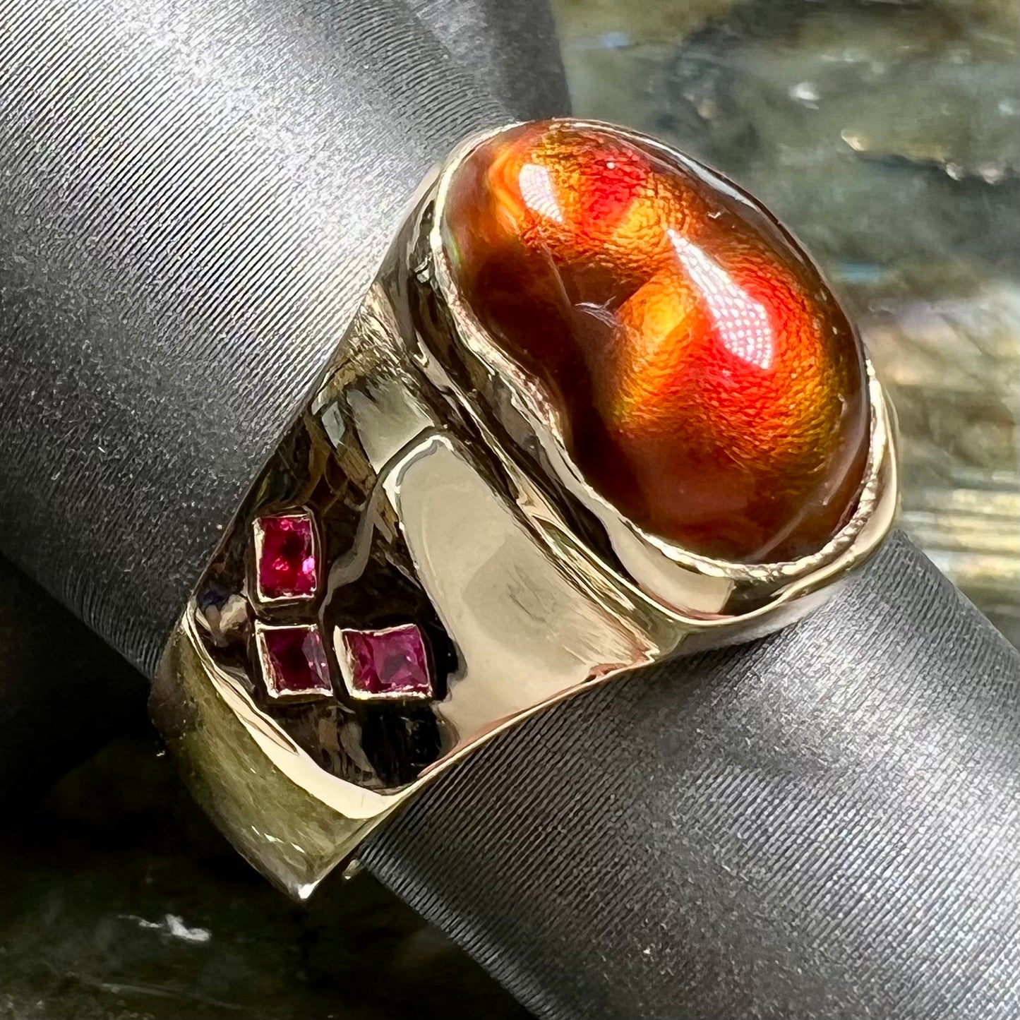 A yellow gold men's ring set with princess cut Burma rubies and a freeform cabochon cut red fire agate from Slaughter Mountain, Arizona.