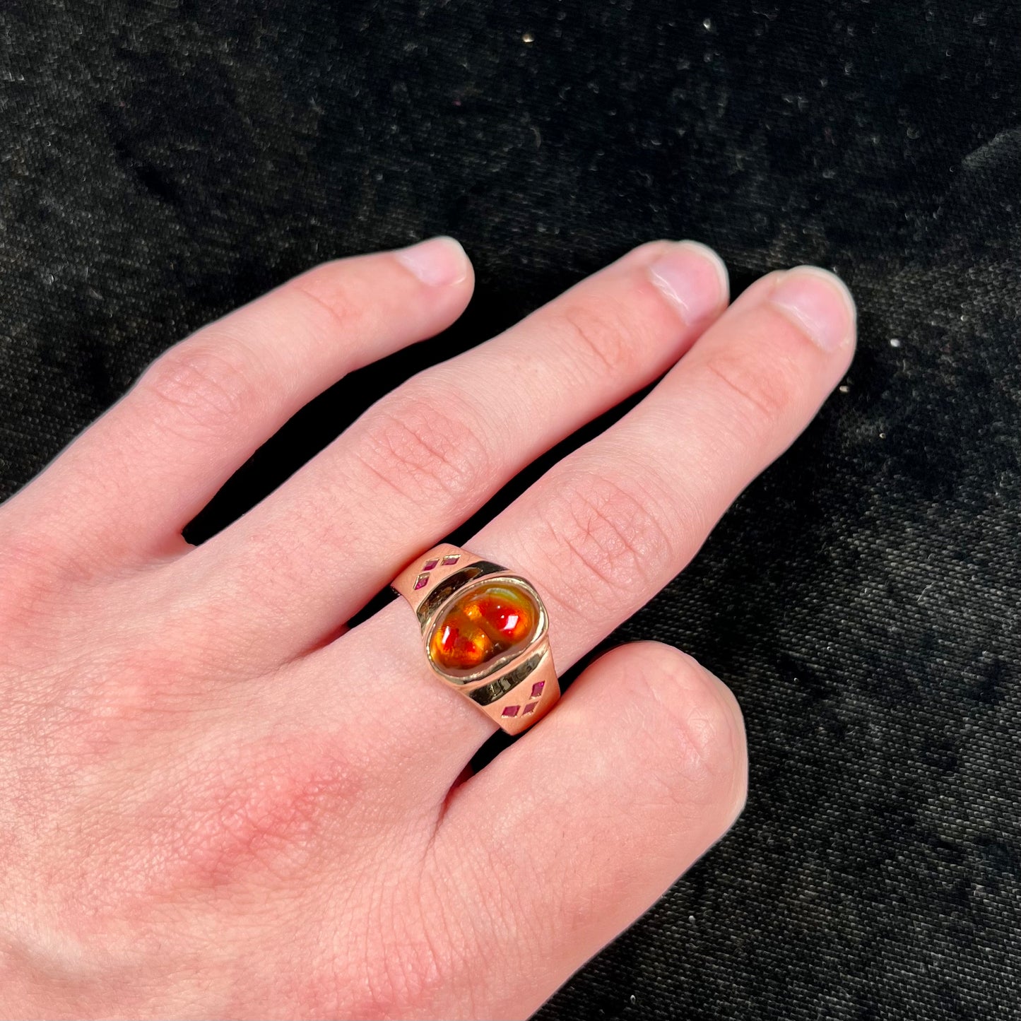 A yellow gold men's ring set with princess cut Burma rubies and a freeform cabochon cut red fire agate from Slaughter Mountain, Arizona.