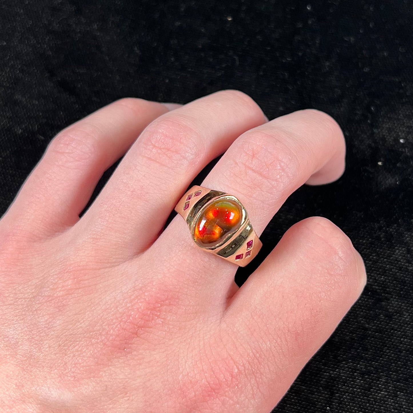 A yellow gold men's ring set with princess cut Burma rubies and a freeform cabochon cut red fire agate from Slaughter Mountain, Arizona.
