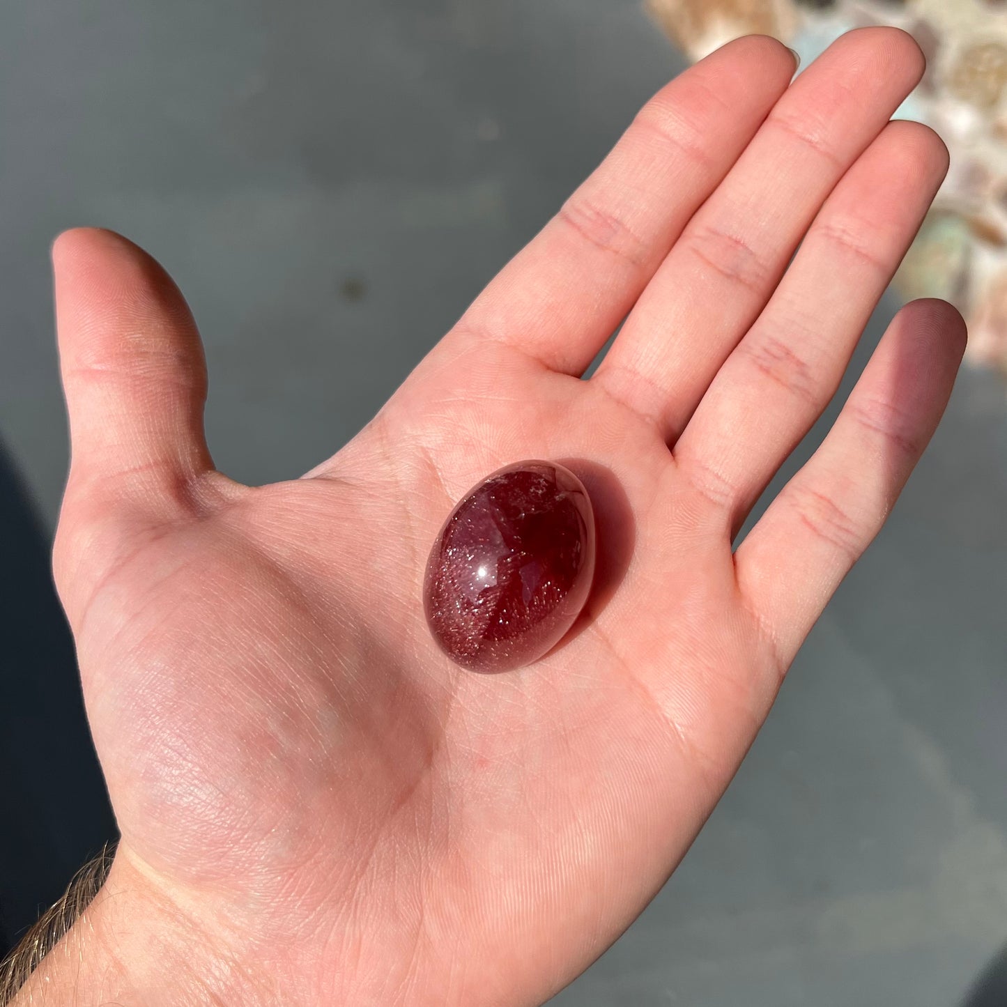 A large, oval cabochon cut strawberry quartz. The stone has a trapiche star-like pattern.