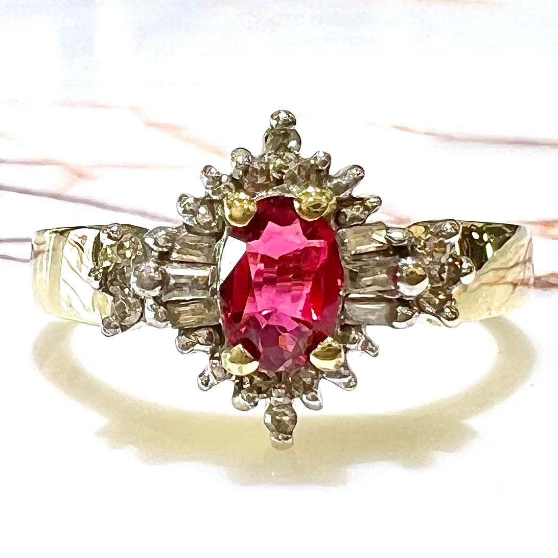 A yellow gold ring set with an oval cut red spinel and diamond rounds and baguettes.