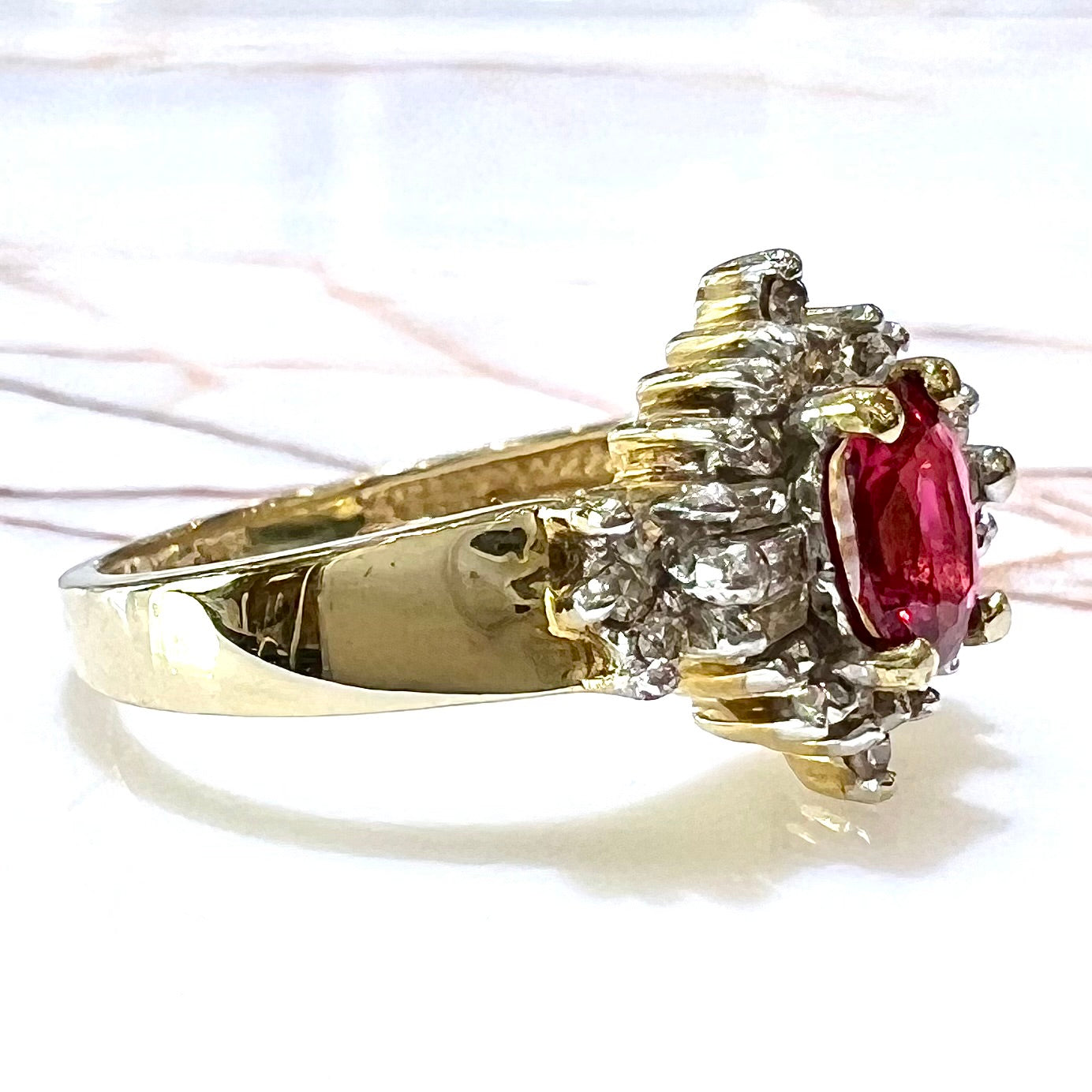 A yellow gold ring set with an oval cut red spinel and diamond rounds and baguettes.