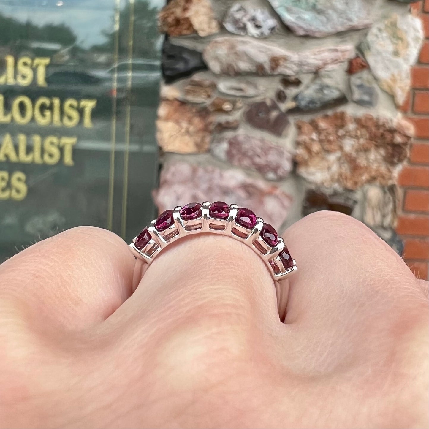 A sterling silver band set with 7 oval cut, purple rhodolite garnet stones.