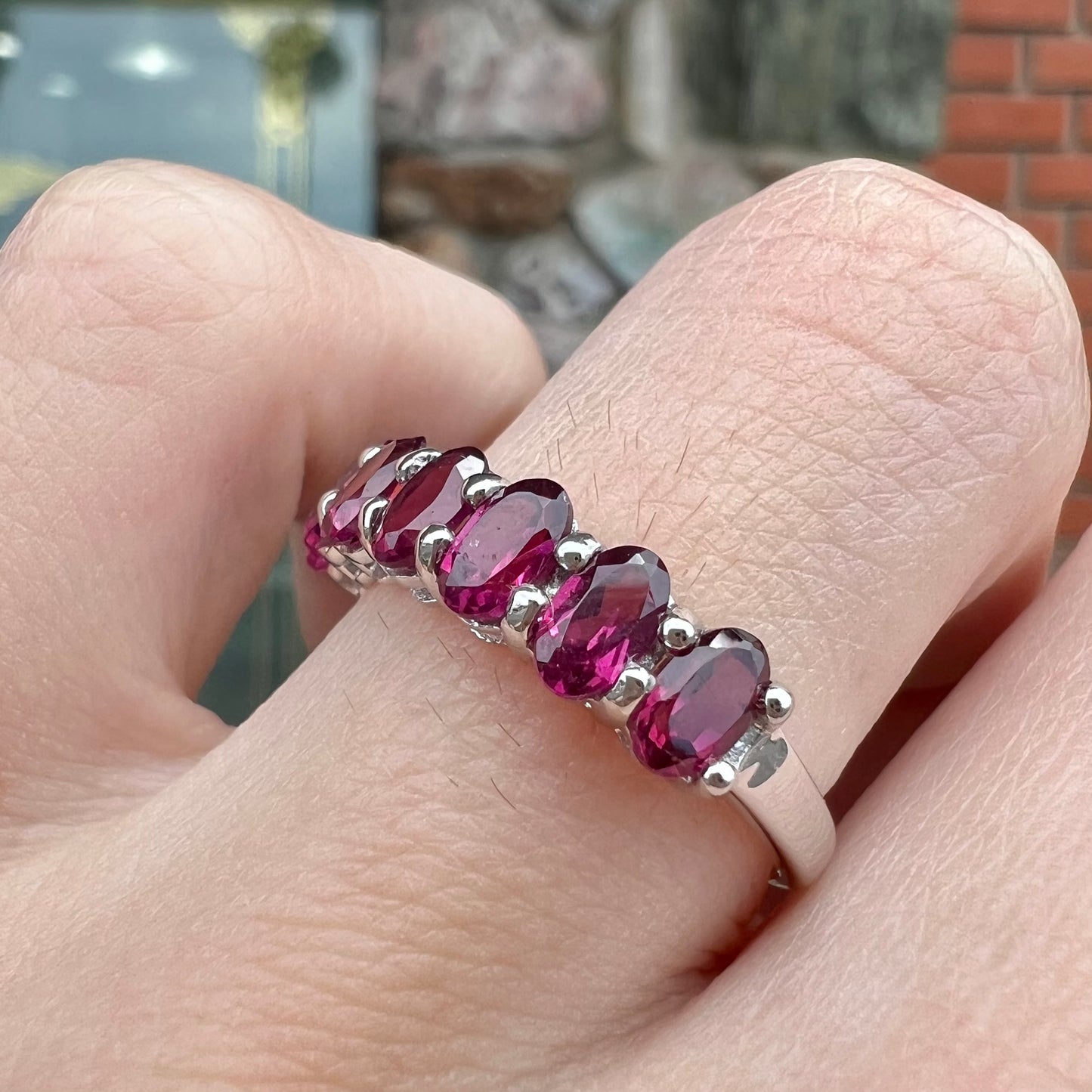 A sterling silver band set with 7 oval cut, purple rhodolite garnet stones.