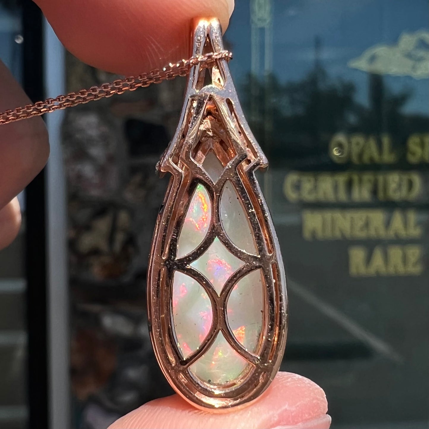 A rose gold, teardrop shaped fire opal and diamond necklace on a cable chain.