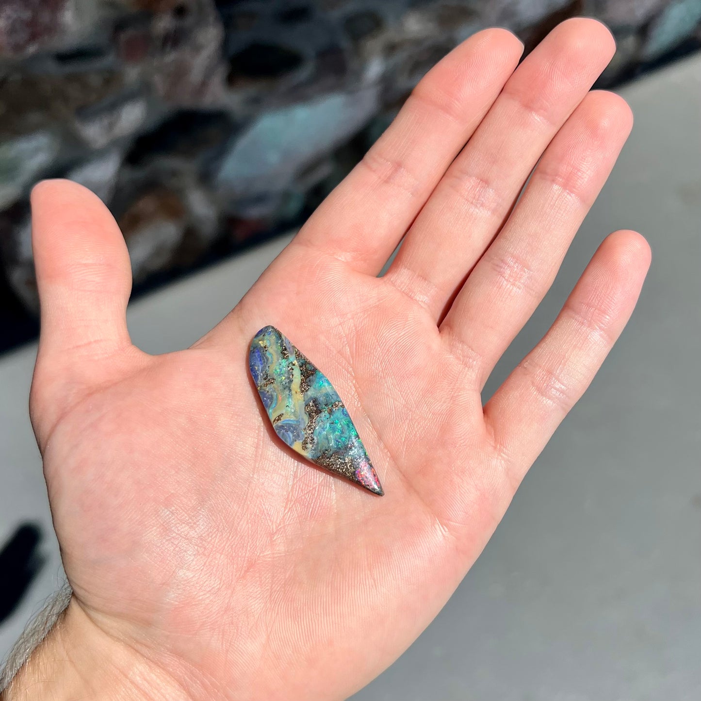 A loose Quilpie boulder opal stone. The stone is blue and has a bright rainbow tip.