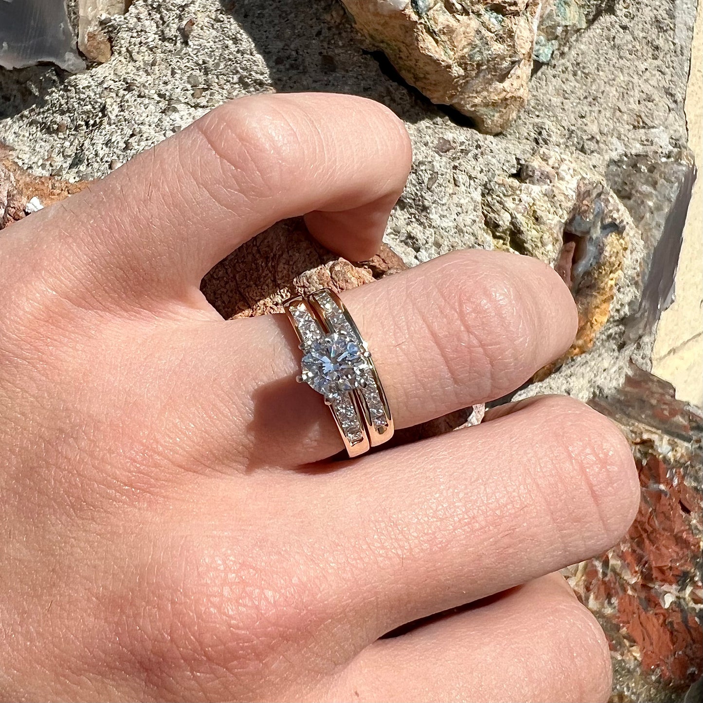 A diamond engagement and wedding ring set. The center stone is a 1 carat round diamond, and the side stones are channel set princess cut diamonds.