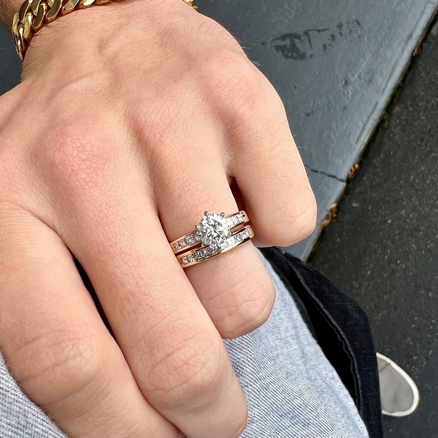 A diamond engagement and wedding ring set. The center stone is a 1 carat round diamond, and the side stones are channel set princess cut diamonds.