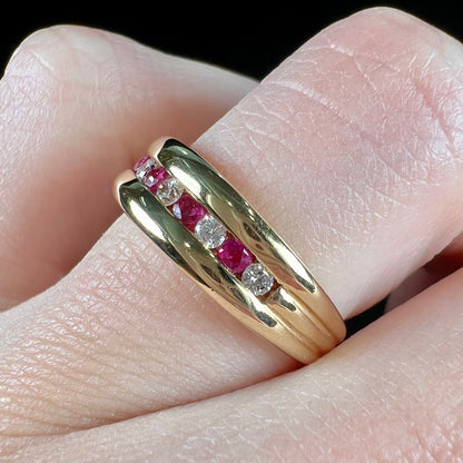 An 18kt yellow gold band channel set with round cut rubies and diamonds.