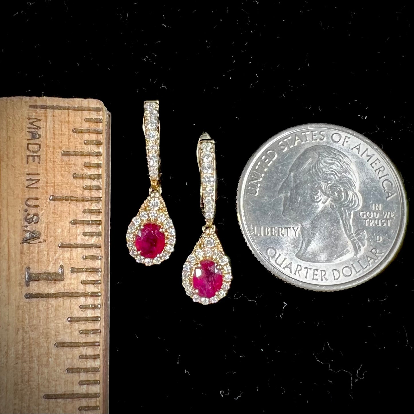 A pair of ruby and diamod halo dangle earrings cast in 14k yellow gold.