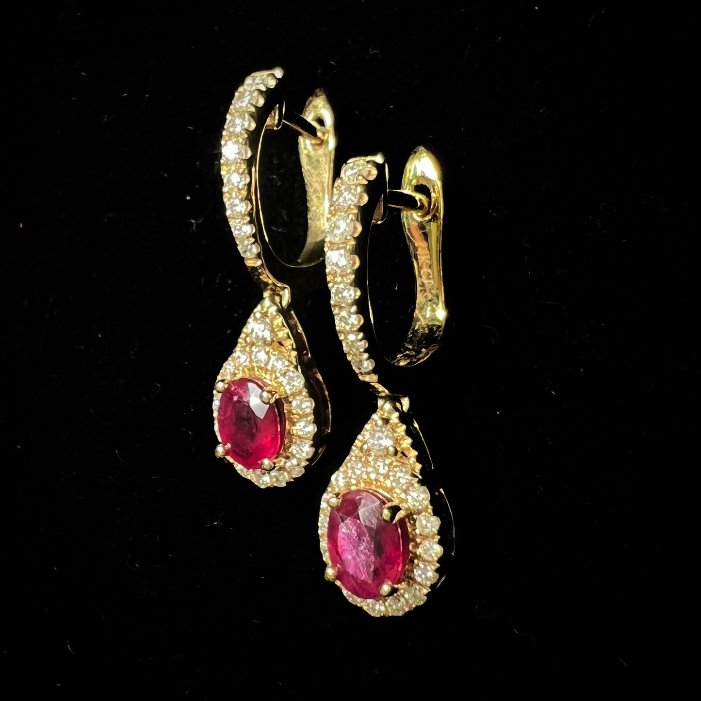A pair of ruby and diamod halo dangle earrings cast in 14k yellow gold.