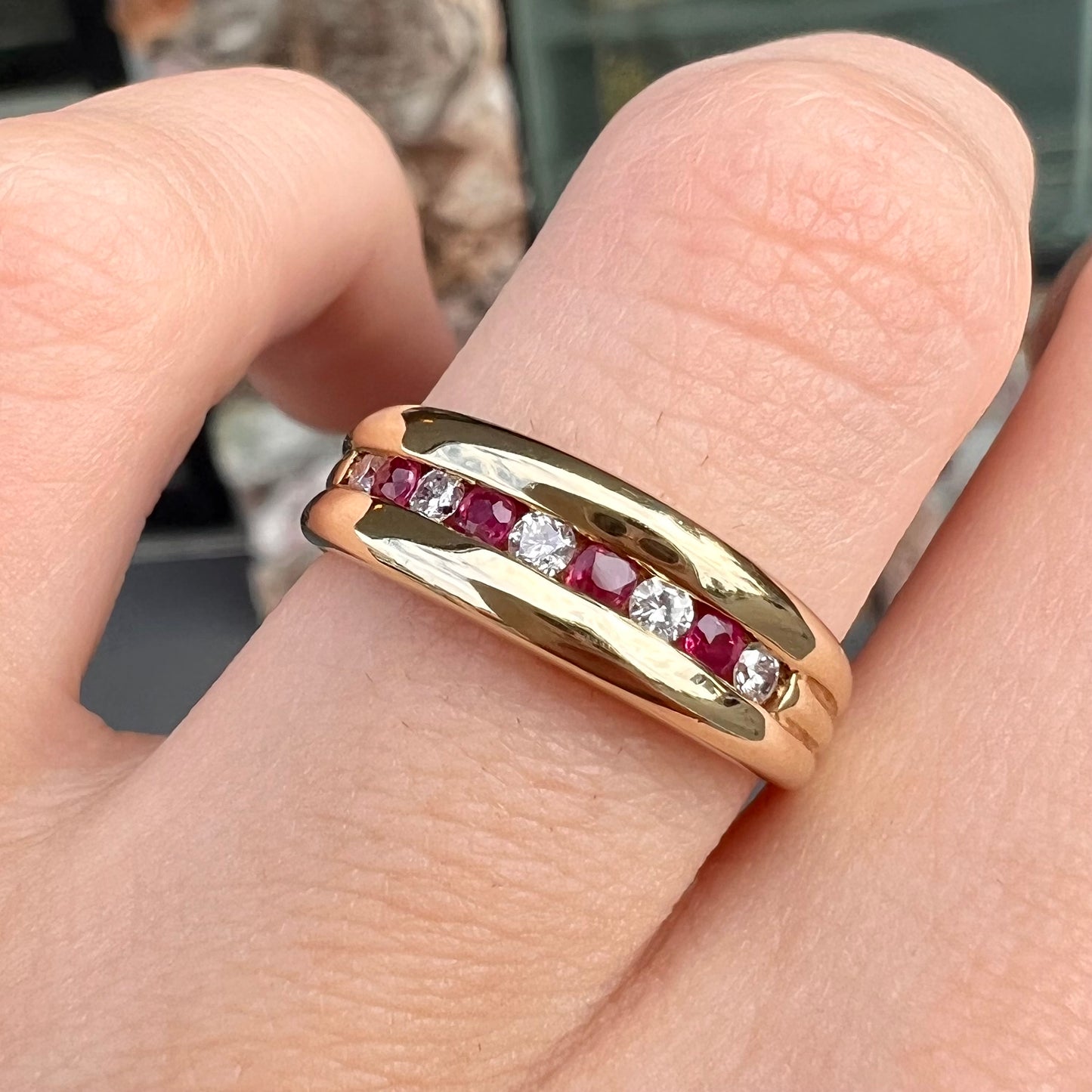 An 18kt yellow gold band channel set with round cut rubies and diamonds.