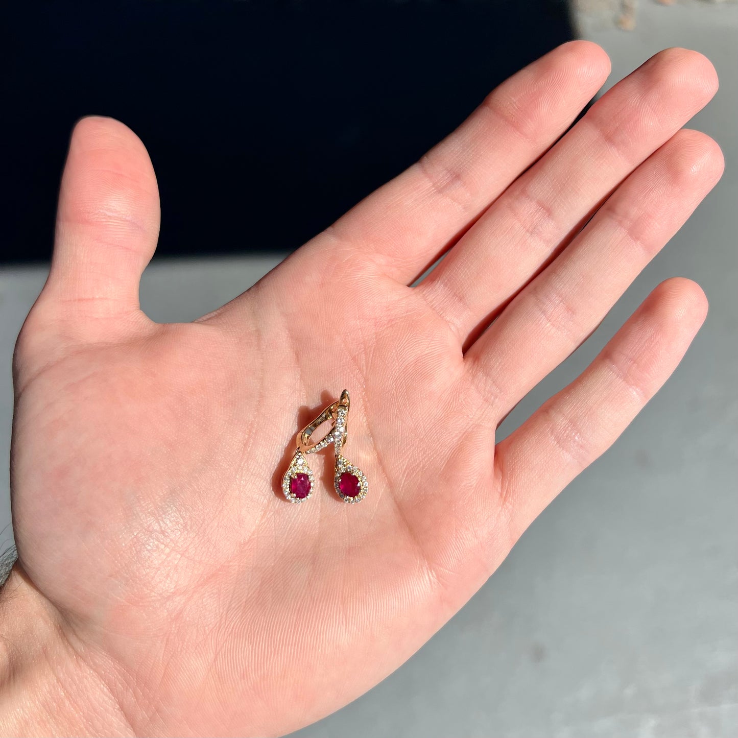 A pair of ruby and diamod halo dangle earrings cast in 14k yellow gold.