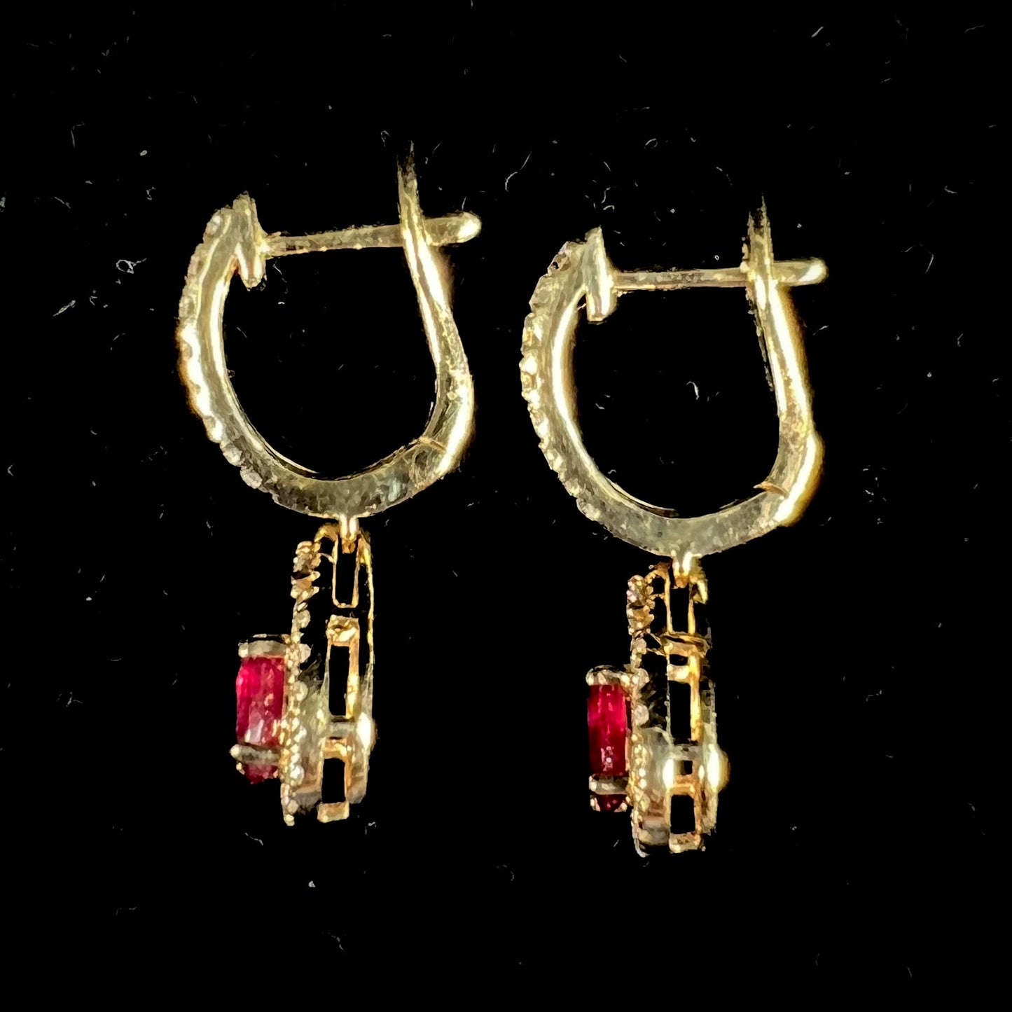 A pair of ruby and diamod halo dangle earrings cast in 14k yellow gold.