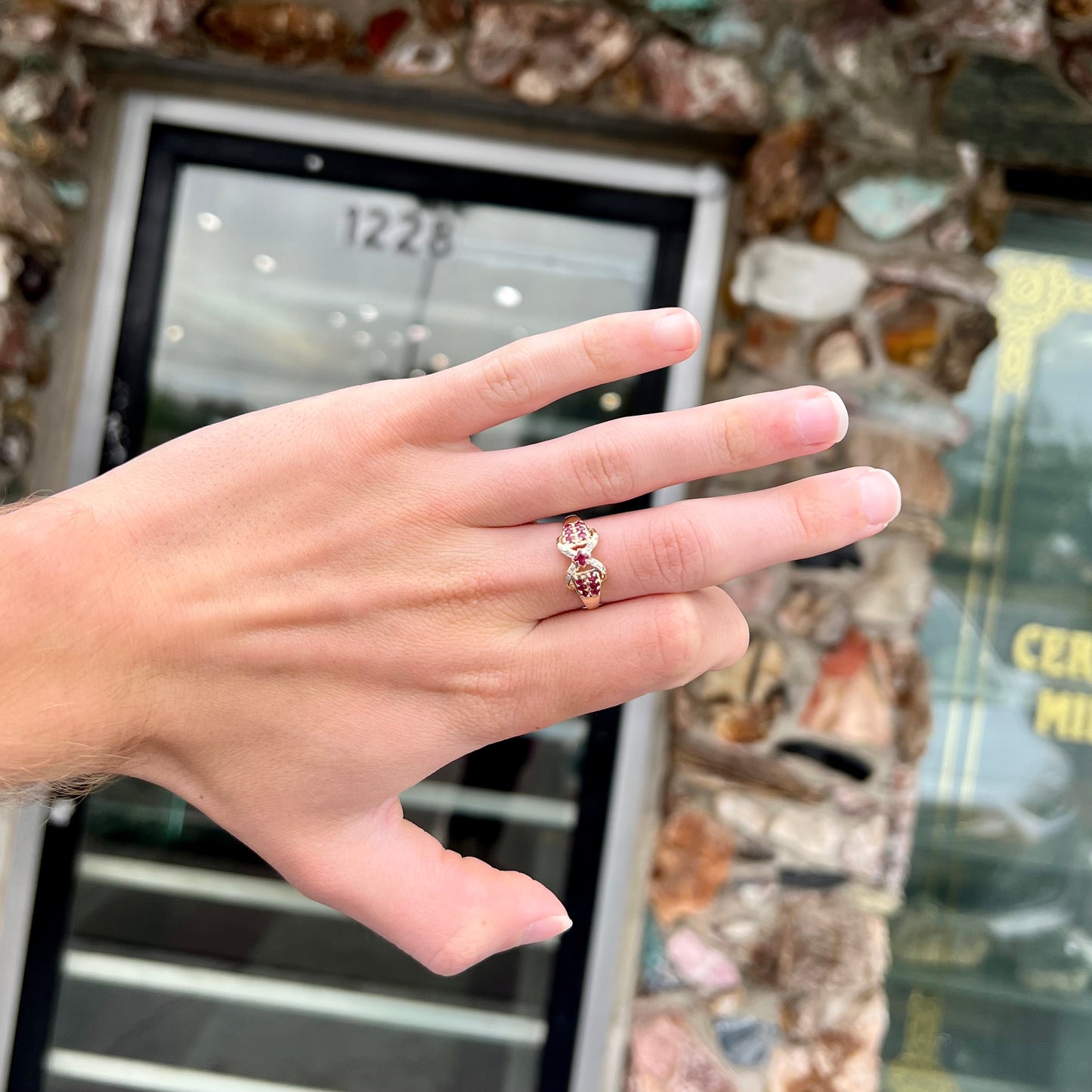 A yellow gold princess cut ruby ring set with round ruby and diamond accents.