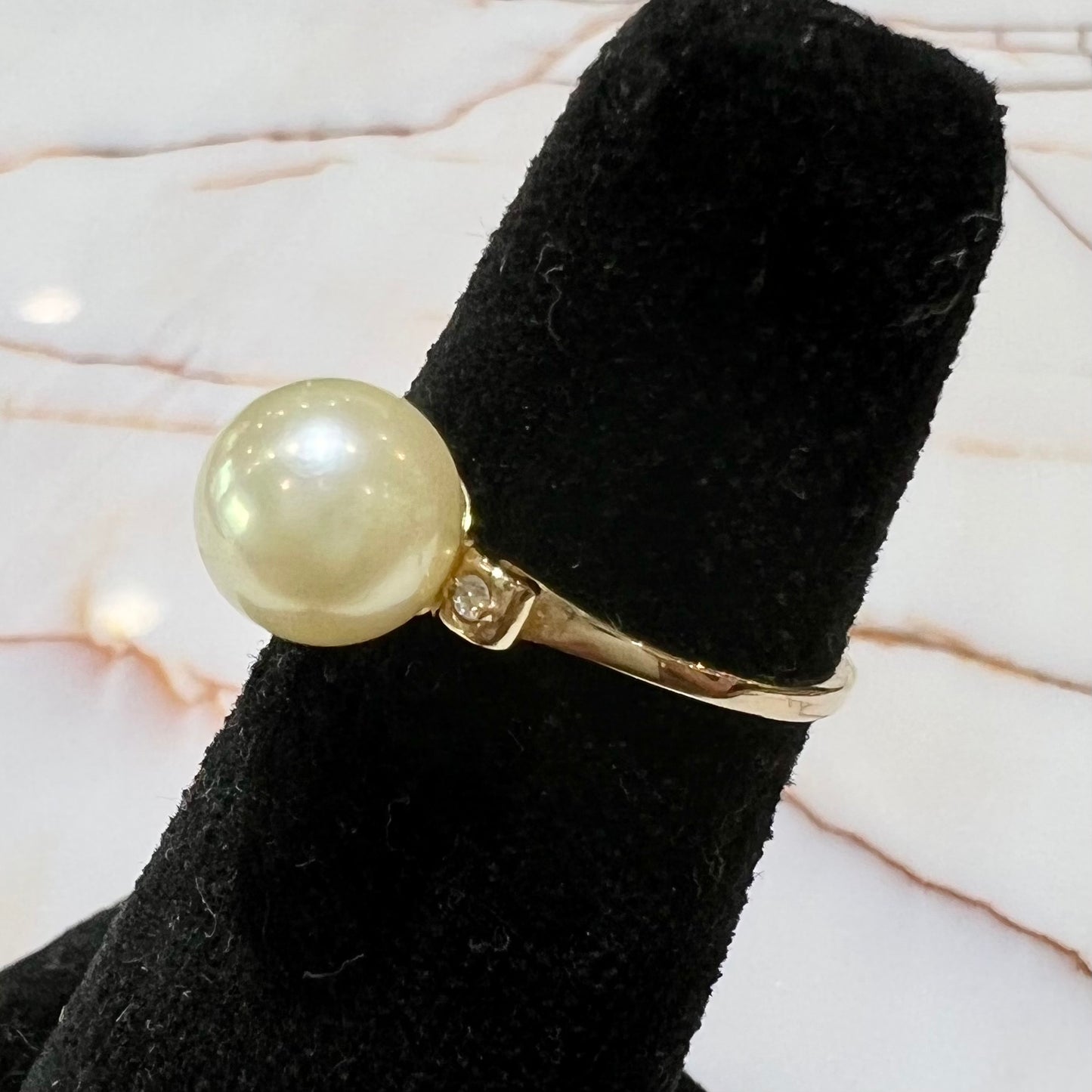 A simple, vintage, yellow gold pearl ring set with two side diamonds.