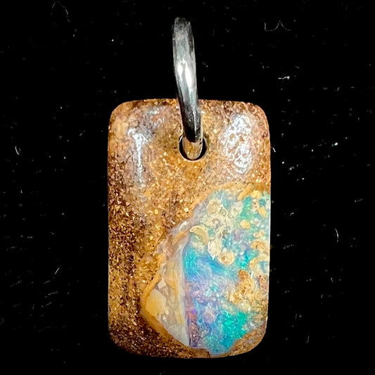 A drilled boulder opal stone with a sterling silver ring through the hole to be worn as a pendant.