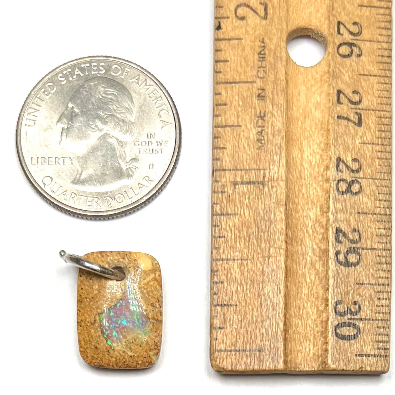 A drilled boulder opal stone with a sterling silver ring through the hole to be worn as a pendant.