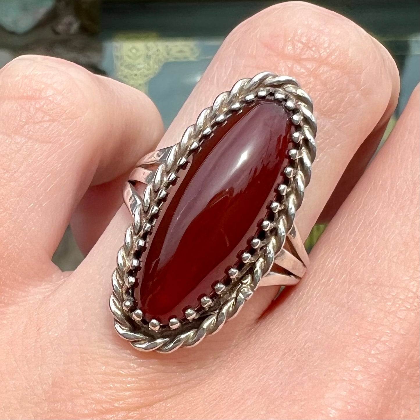 A split shank silver ring set with a brown sard stone in a rope bezel with small prongs.