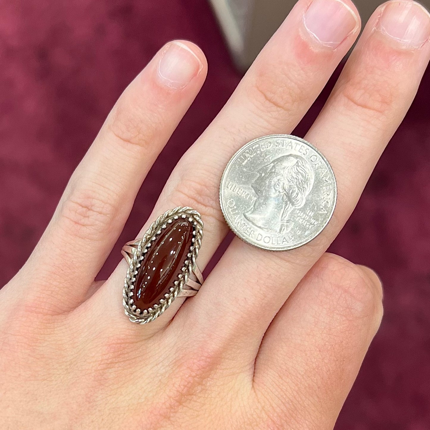 A split shank silver ring set with a brown sard stone in a rope bezel with small prongs.