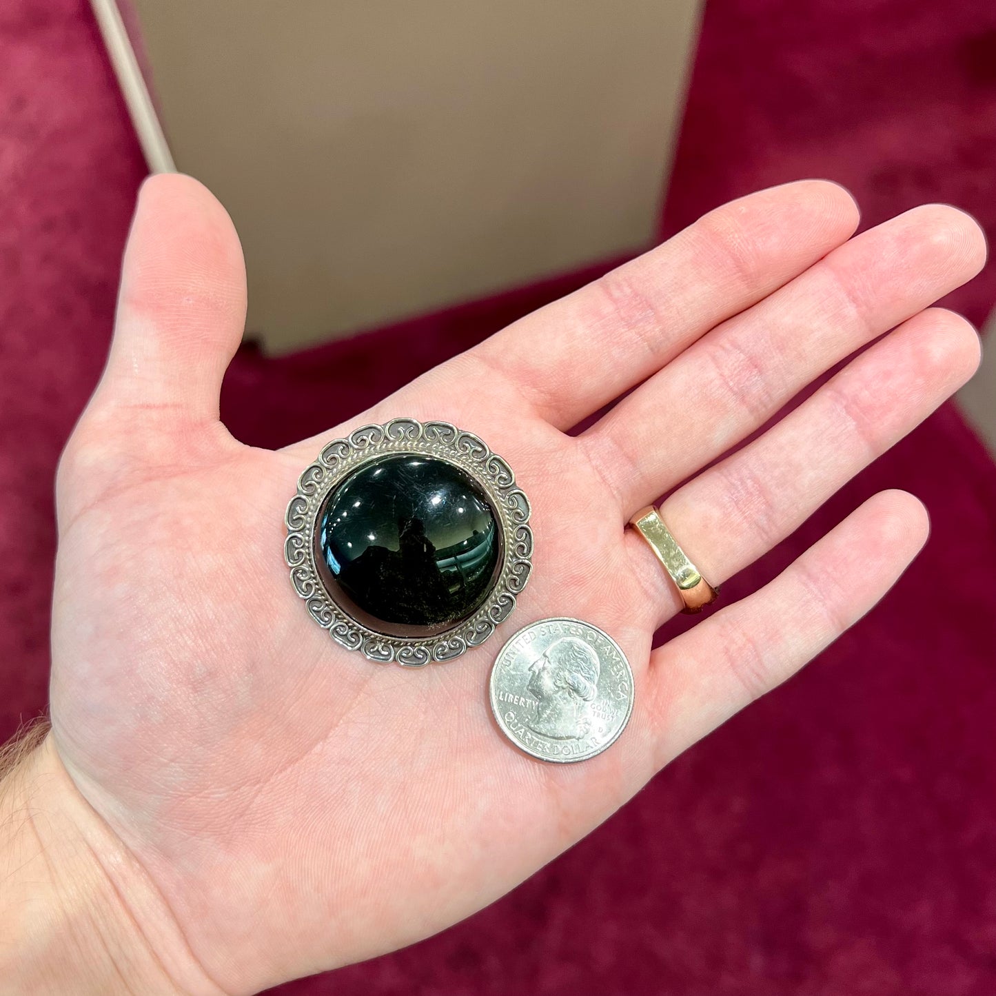 A sterling silver pendant/brooch bezel set with a round cabochon cut black sheen obsidian stone.