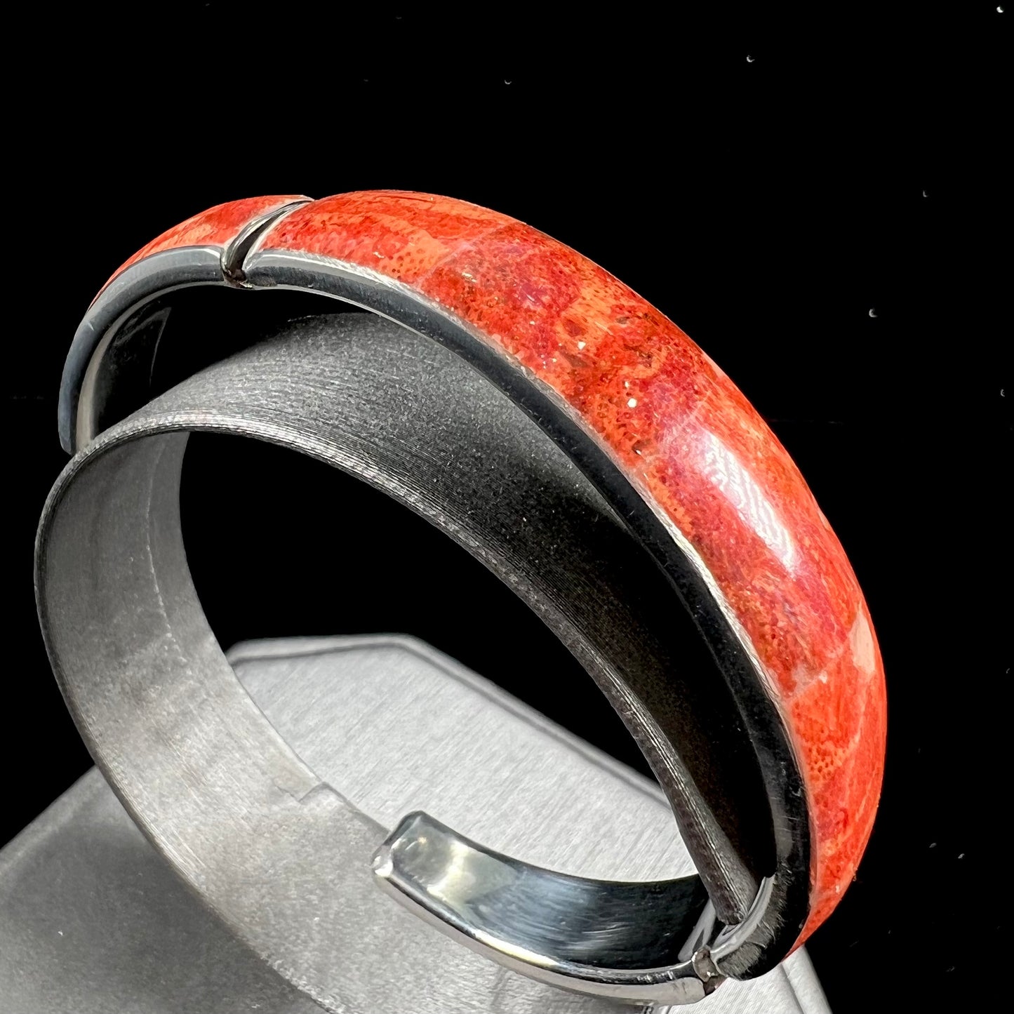 An adjustable stainless steel cuff bracelet inlaid with polished spiny oyster shell.