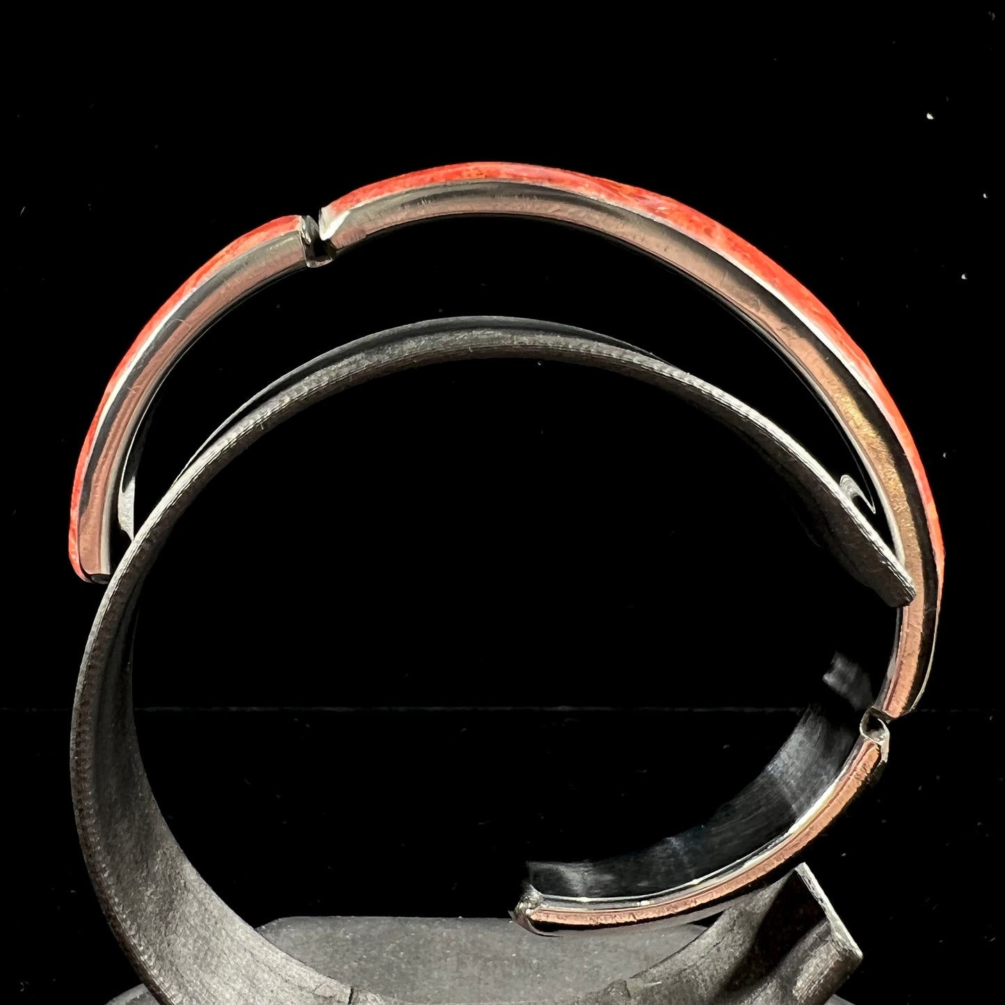 An adjustable stainless steel cuff bracelet inlaid with polished spiny oyster shell.