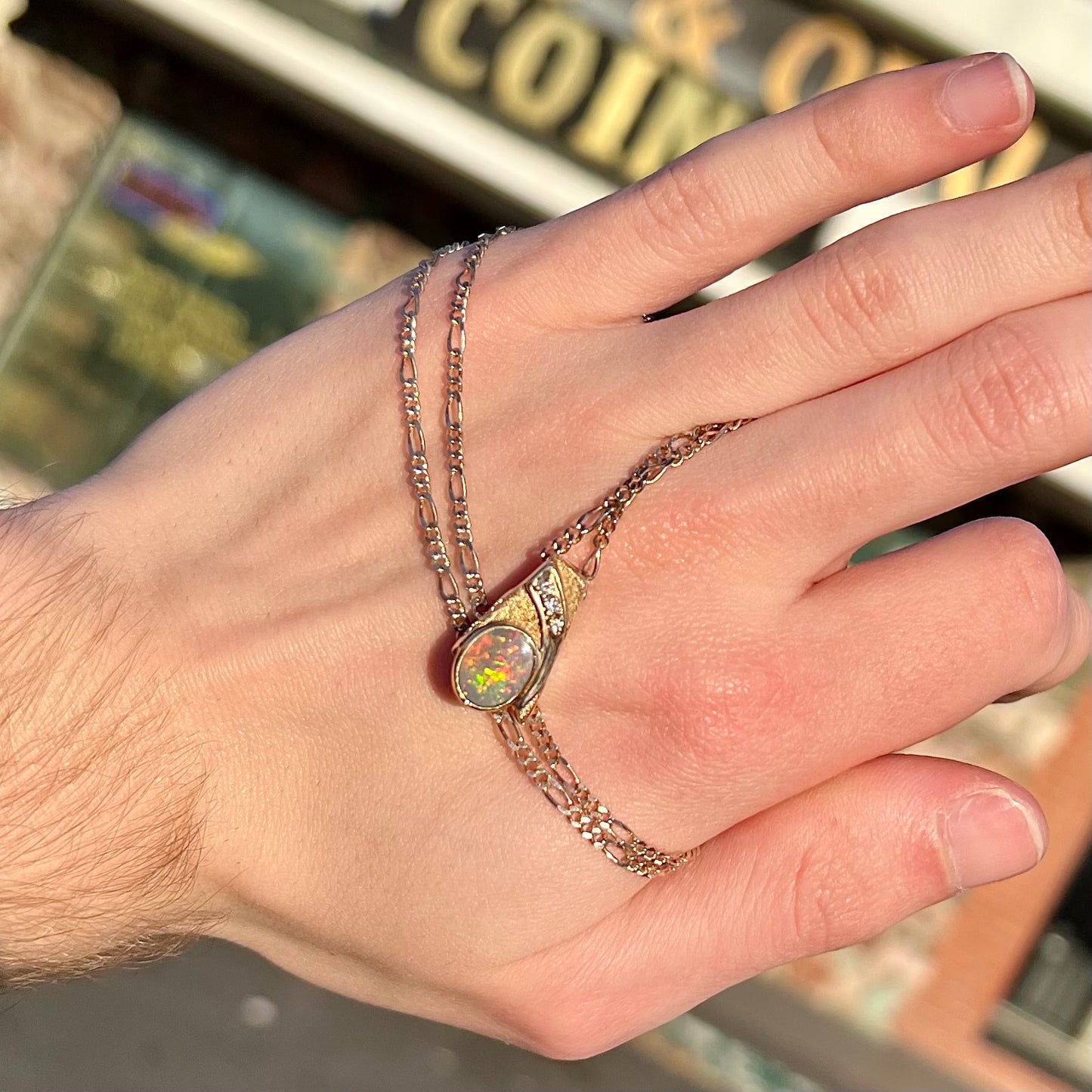 A yellow gold black opal necklace set with three round diamond accents.