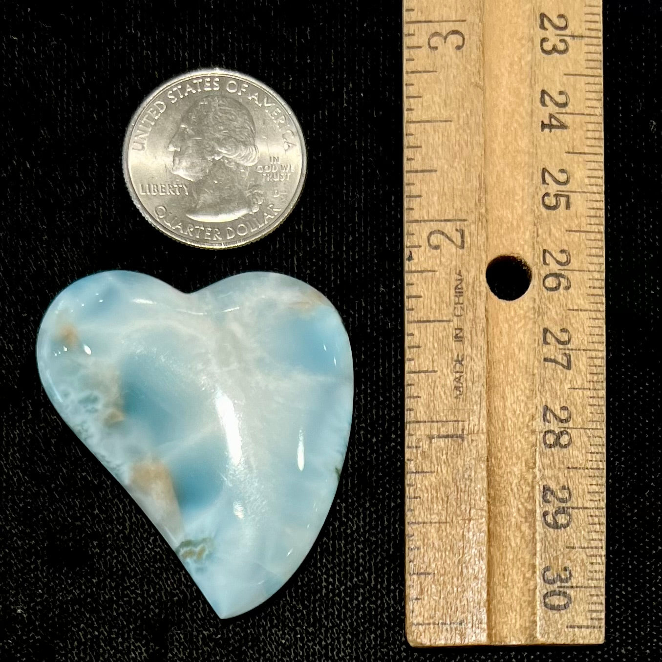 A loose, carved, heart shaped larimar stone. Predominant colors are blue and white.