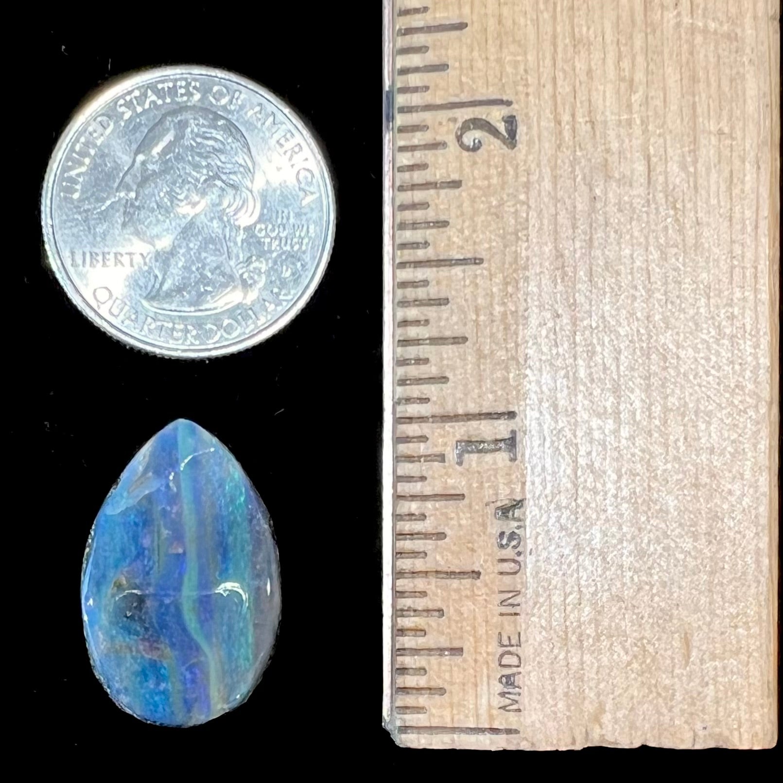 A loose, pear shaped Australian boulder opal stone.  The predominant colors are purple, green, and aqua.