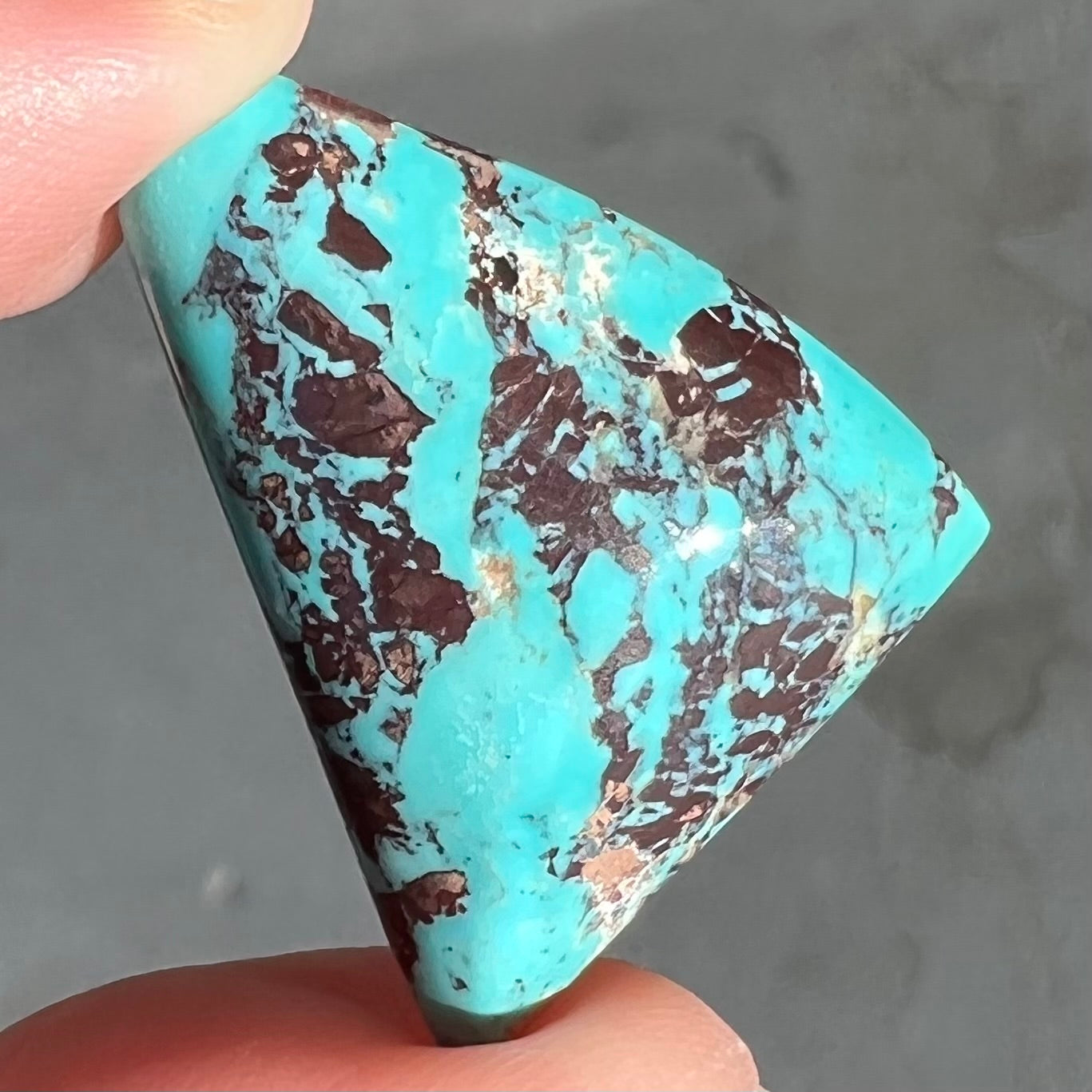 A triangular cabochon cut blue turquoise with red matrix from Mohave County, Arizona.