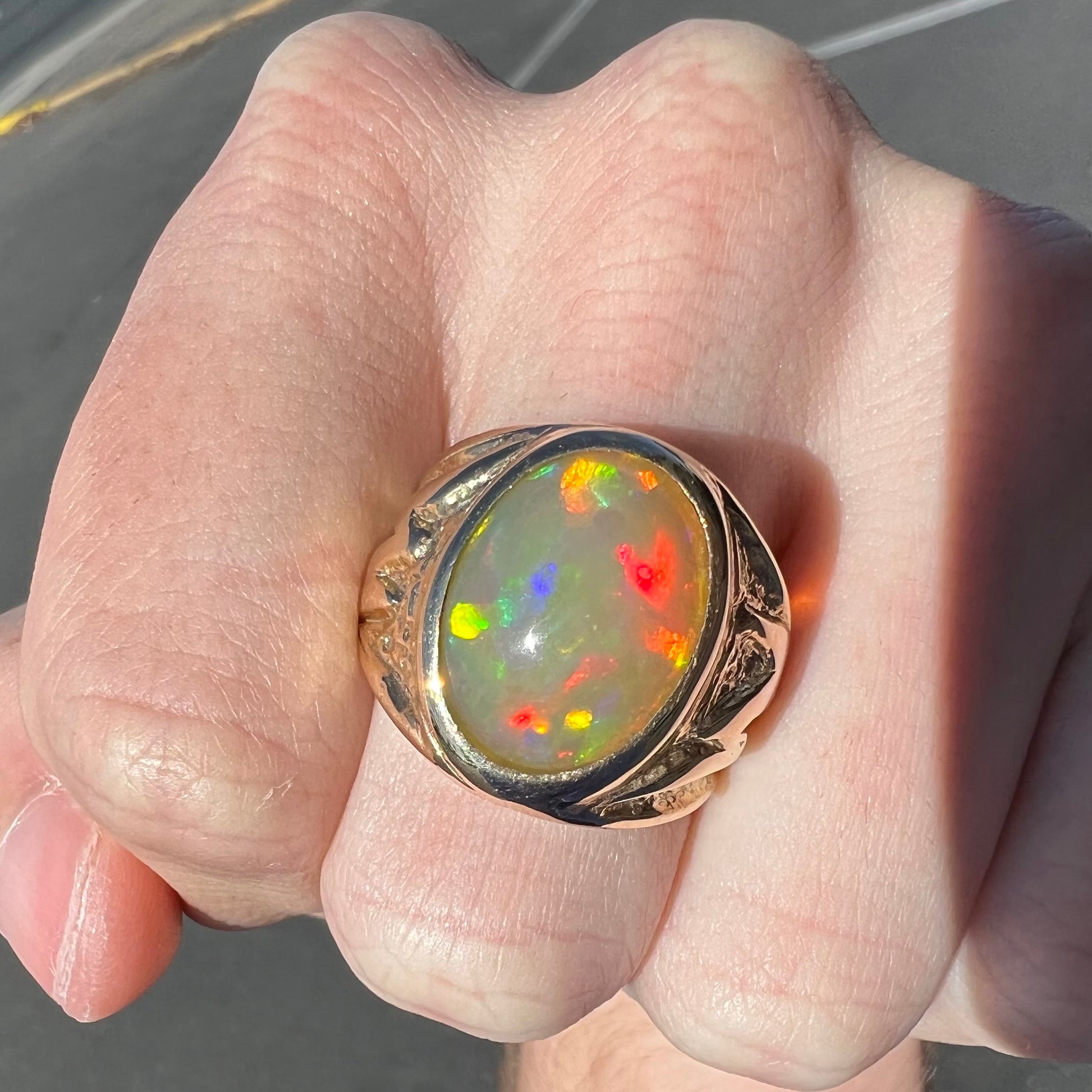 A solid yellow gold solitaire men's fire opal ring.  The stone is an orange oval cabochon cut.