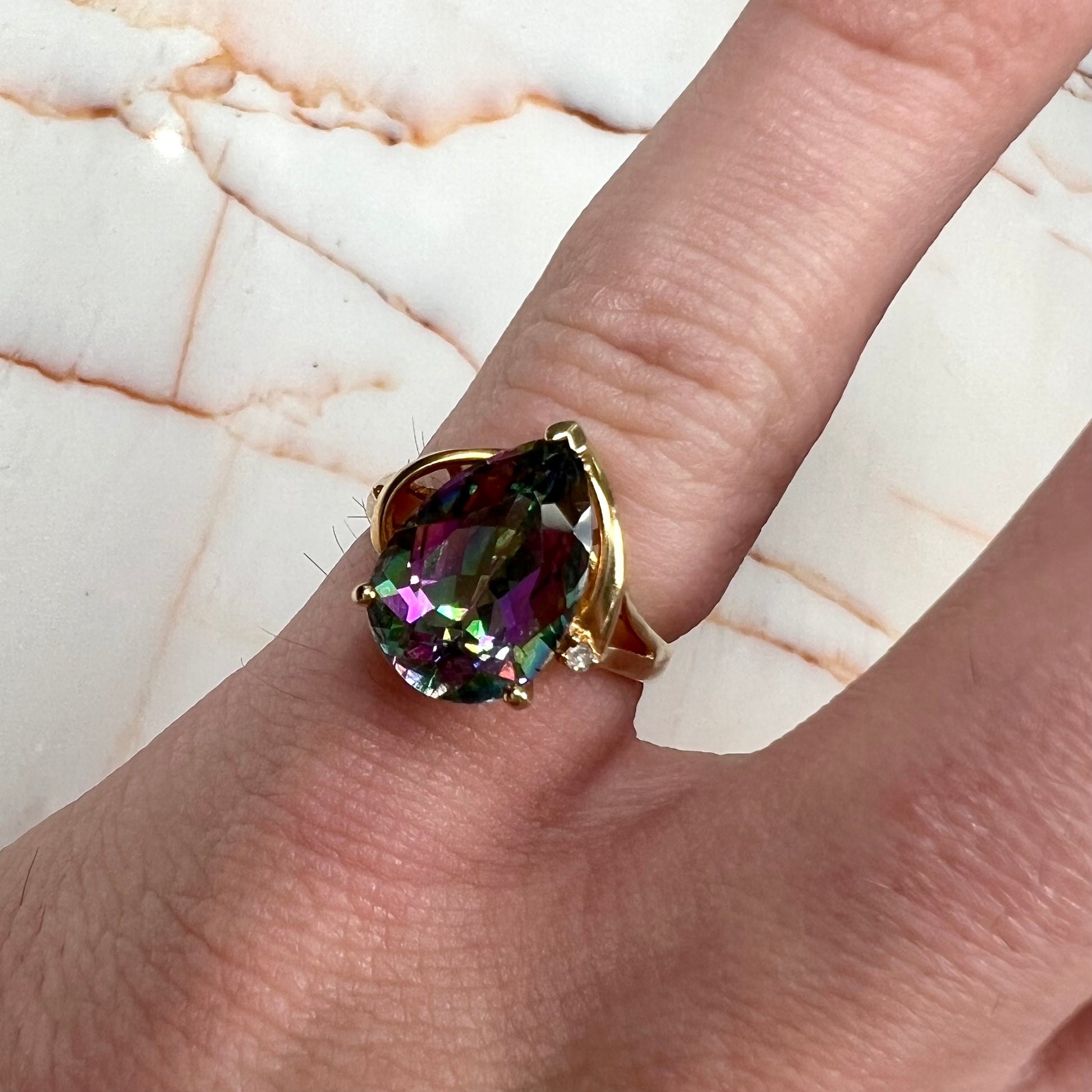 Pear shape green and pink mystic topaz set in a yellow gold ring with a single round diamond.