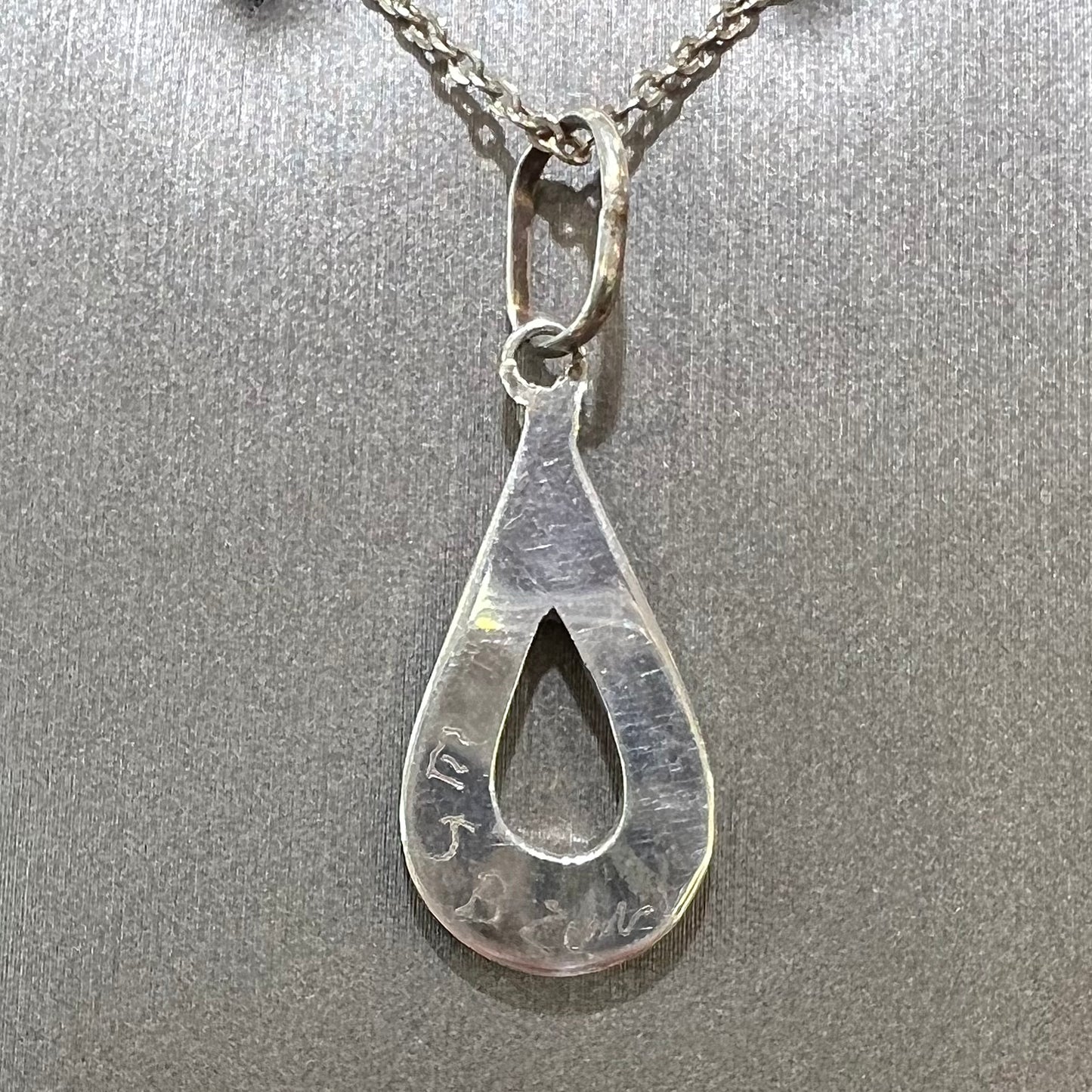 Backside of handmade Zuni Tribe silver pendant, signed "E J B ZUNI."