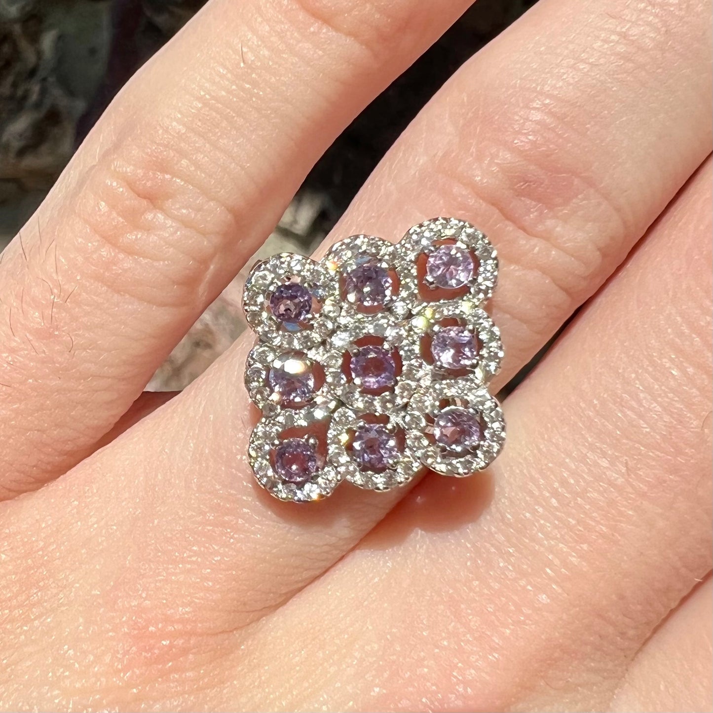 A silver ladies' ring set with 9 rose de France amethyst stones in white topaz halos.