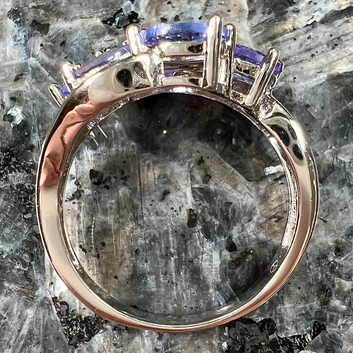 A sterling silver cluster ring prong set with seven faceted oval cut blue tanzanite stones.