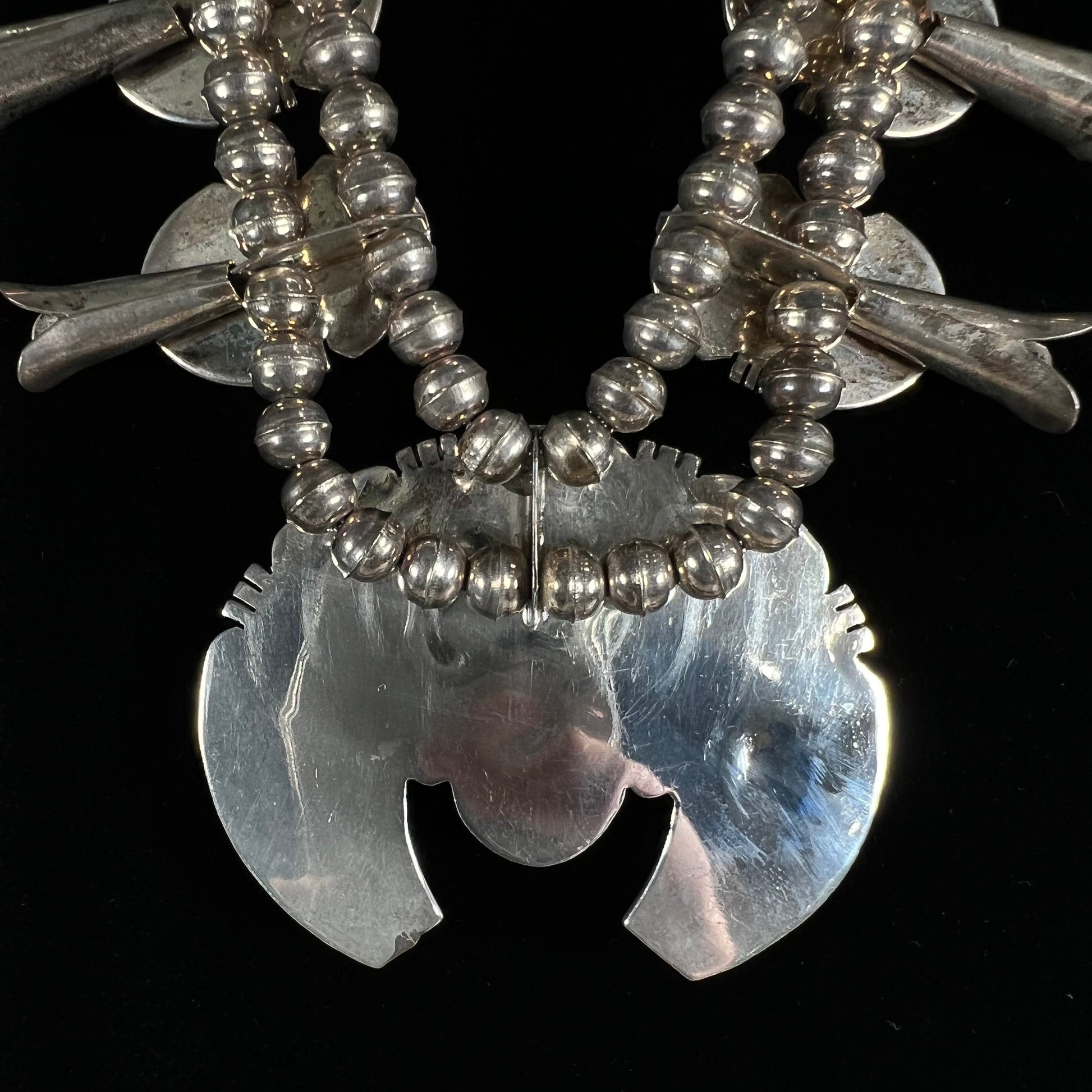A silver Kingman turquoise squash blossom necklace.  The necklace is made with handmade Navajo pearls.