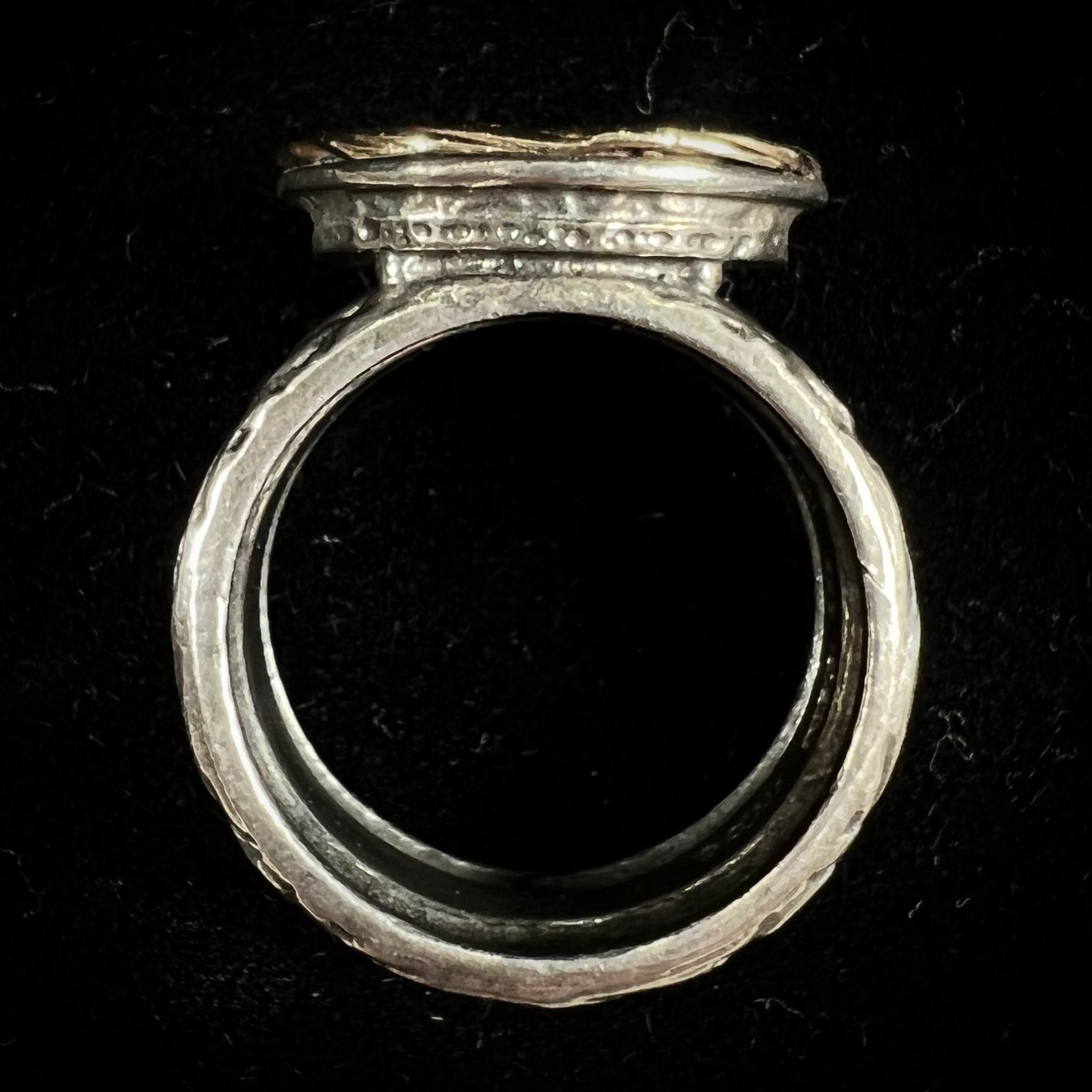 A filigree etched two tone silver and gold spinner ring set with a lab created black opal.