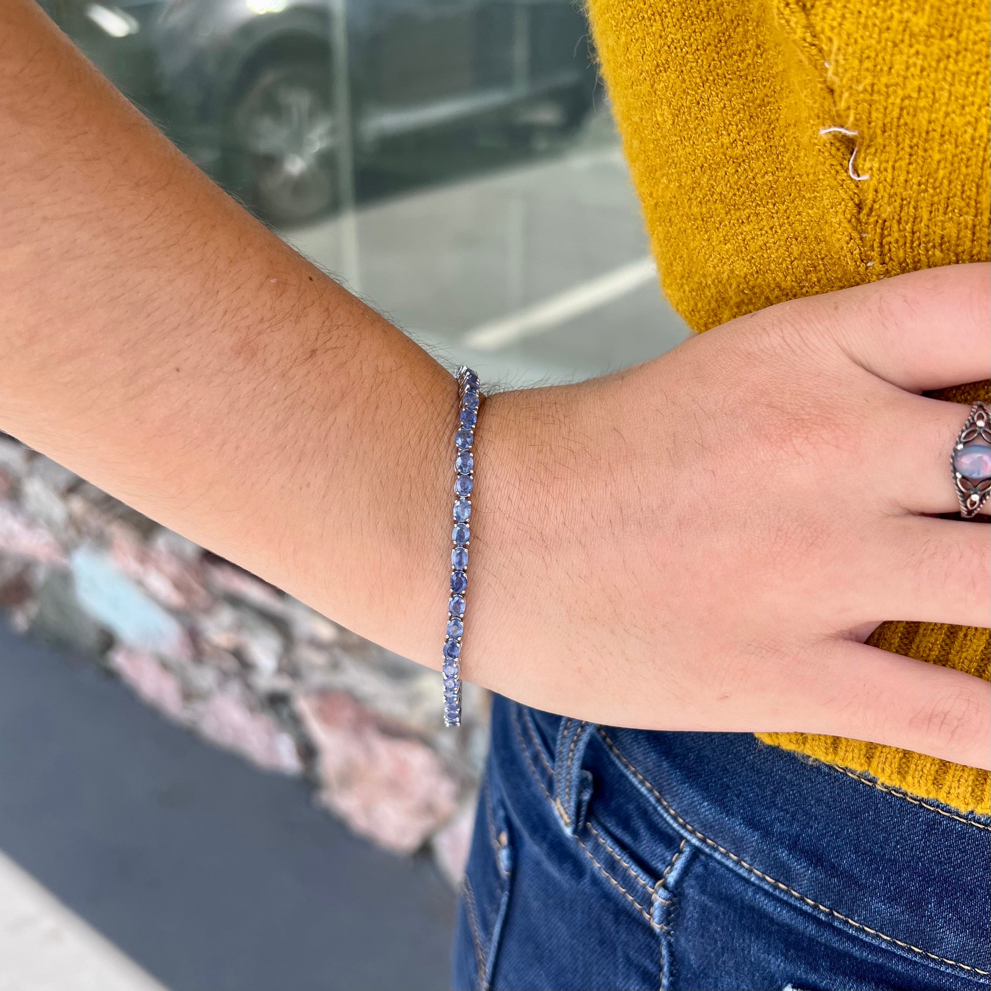 A sterling silver tennis bracelet set with faceted oval cut blue sapphires.