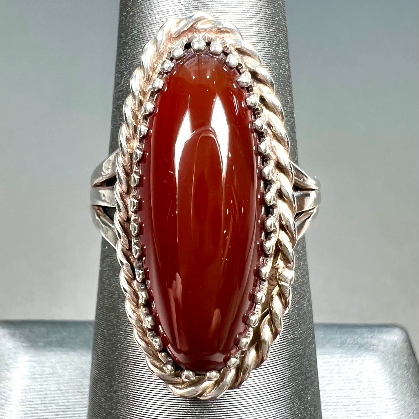 A split shank silver ring set with a brown sard stone in a rope bezel with small prongs.