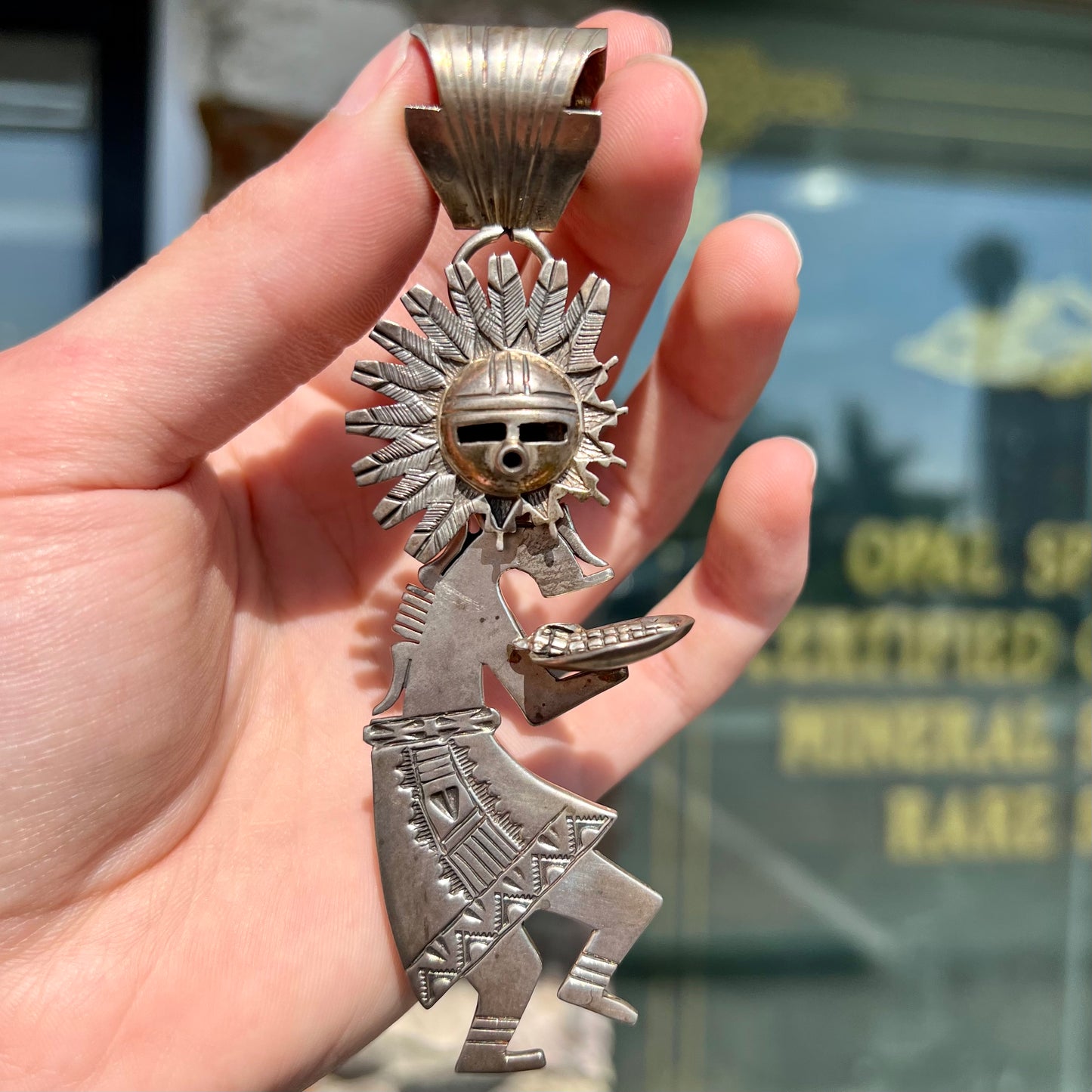 A "Navajo Sunface" kachina doll pendant made from sterling silver by artist Bennie Ration. The piece measures four and a half inches long.