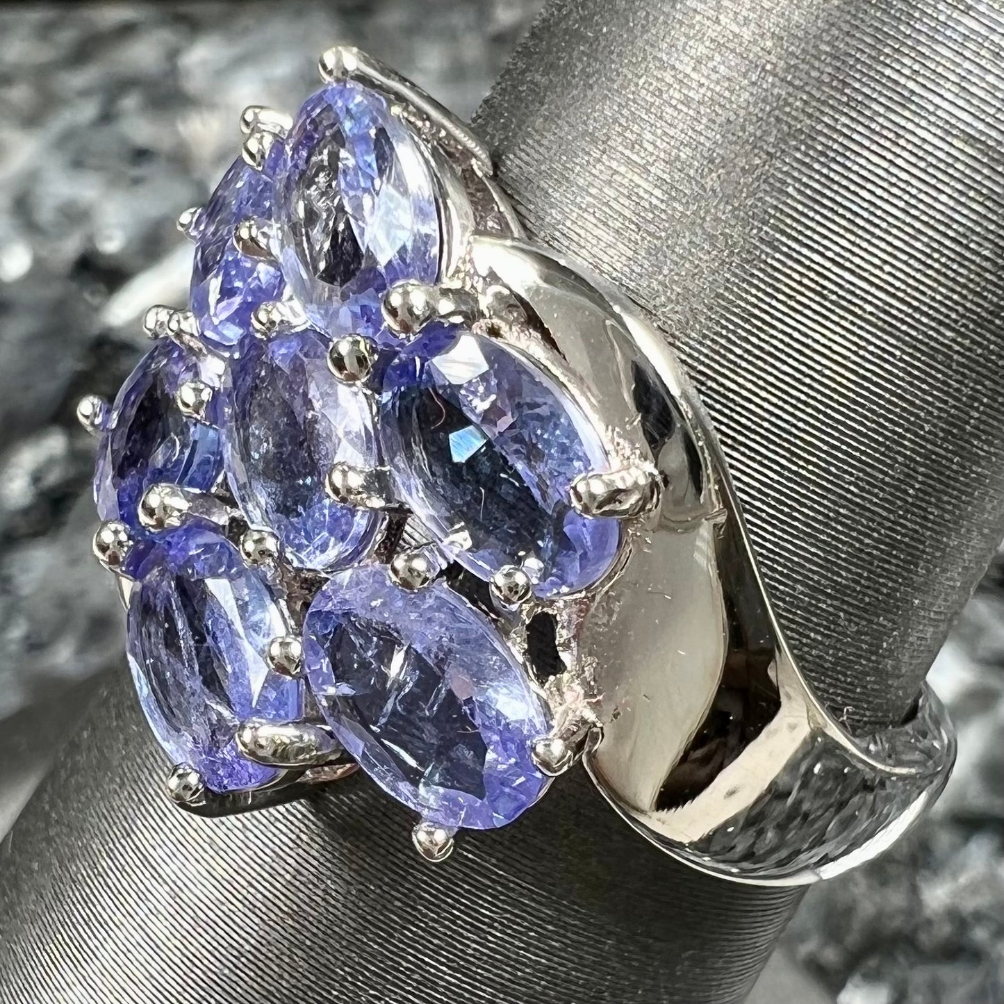 A sterling silver cluster ring prong set with seven faceted oval cut blue tanzanite stones.